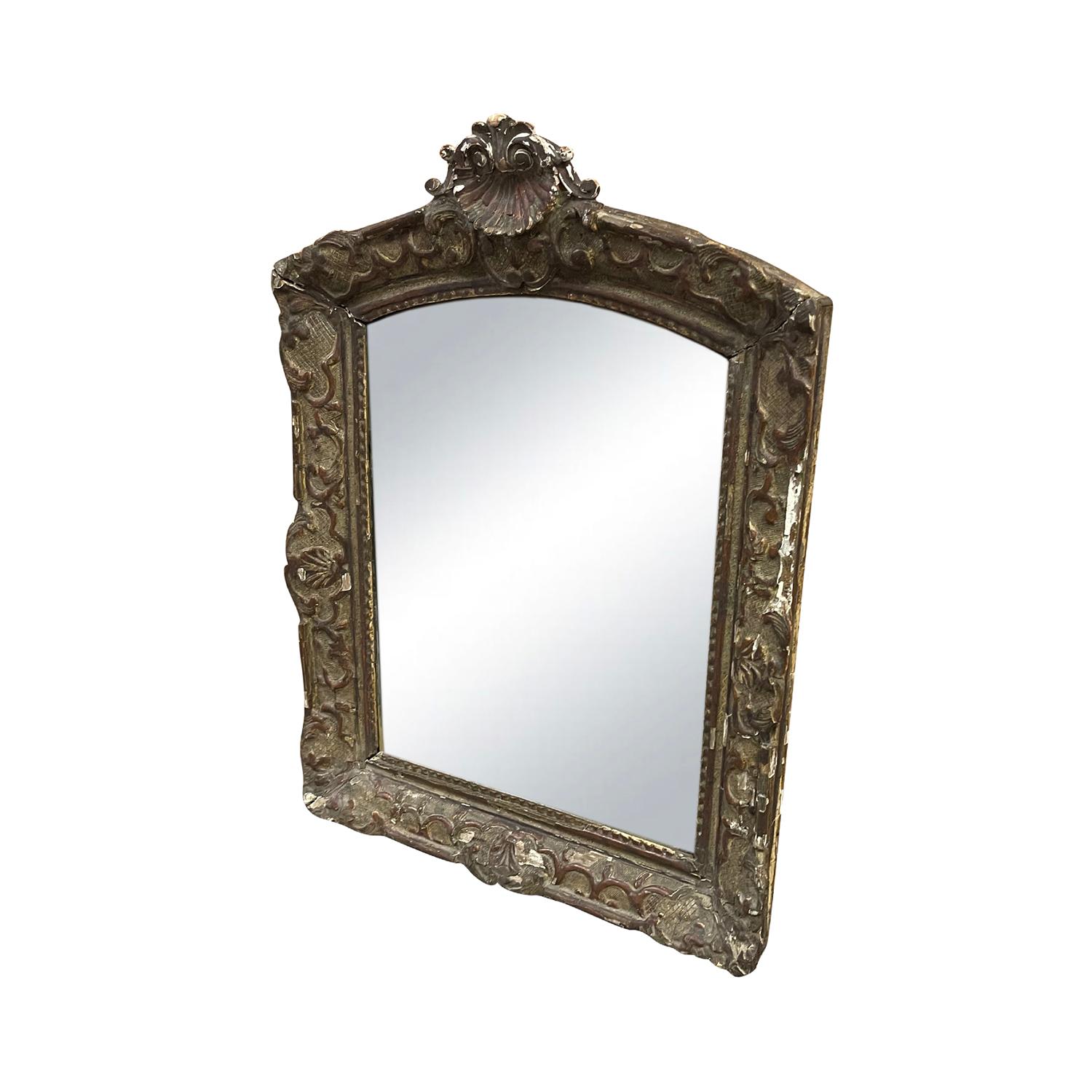 A French 19th century Louis XV style mirror, carved in Pinewood with Gesso finish and gilded, in good condition. The frame has the typical Rocaille décor. The antique mirror has its original mirrored glass. The top of the frame is adorned with a