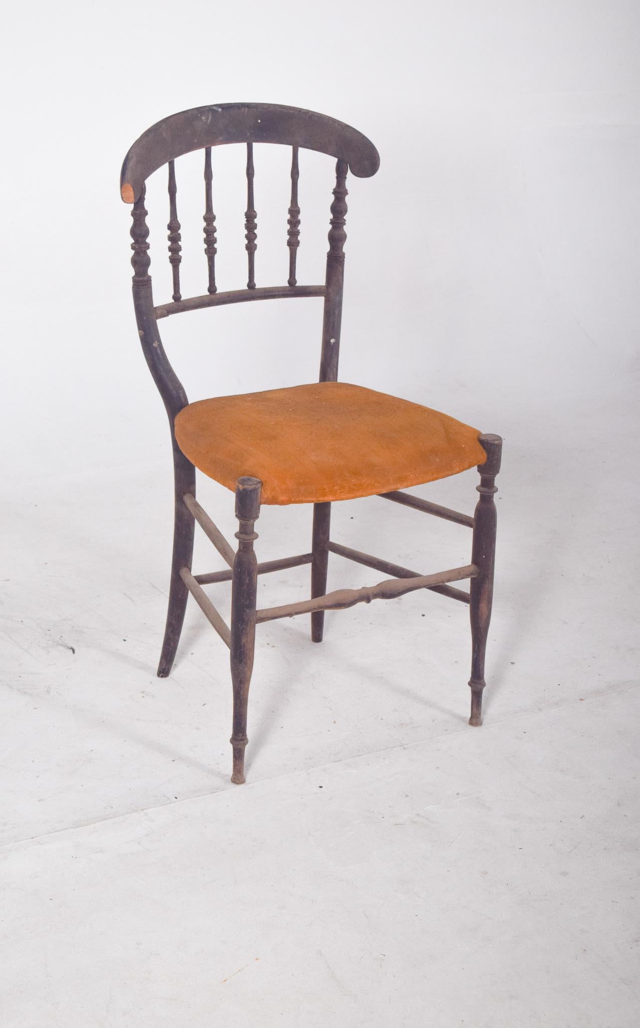 Dark wood dining chair. With a curved back and a backrest made of turned wood that evokes the elegance of 19th century furniture. The structure features fine, turned lines on the legs and crossbars, adding lightness to the overall design. The seat