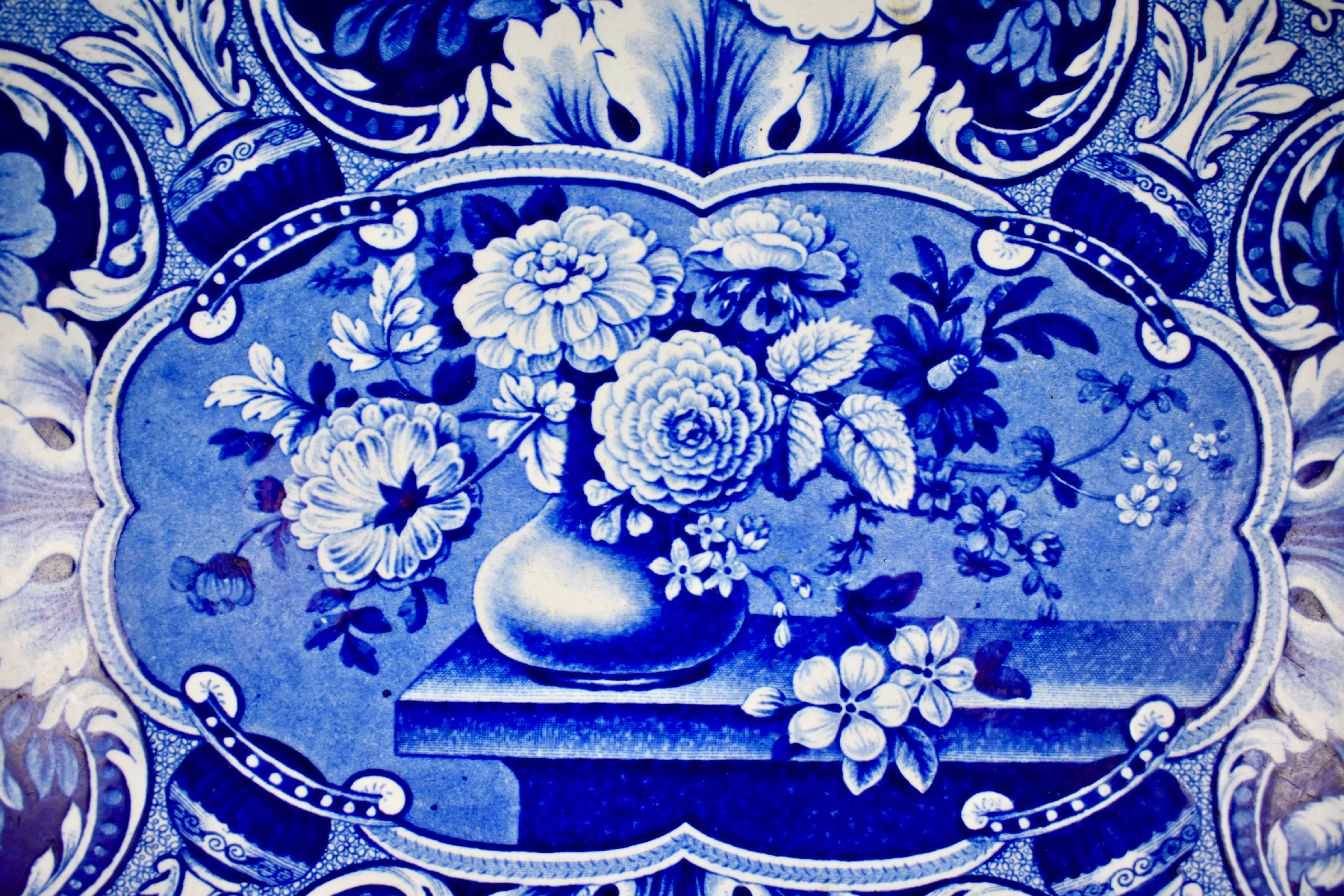 From the Davenport pottery, Longport, Staffordshire, England, an oversize earthenware, underglaze tissue printed platter, in the “Vase with Medallions of Flowers” pattern. 

An impressed mark on the verso used circa 1815-1860.

A complex blue on