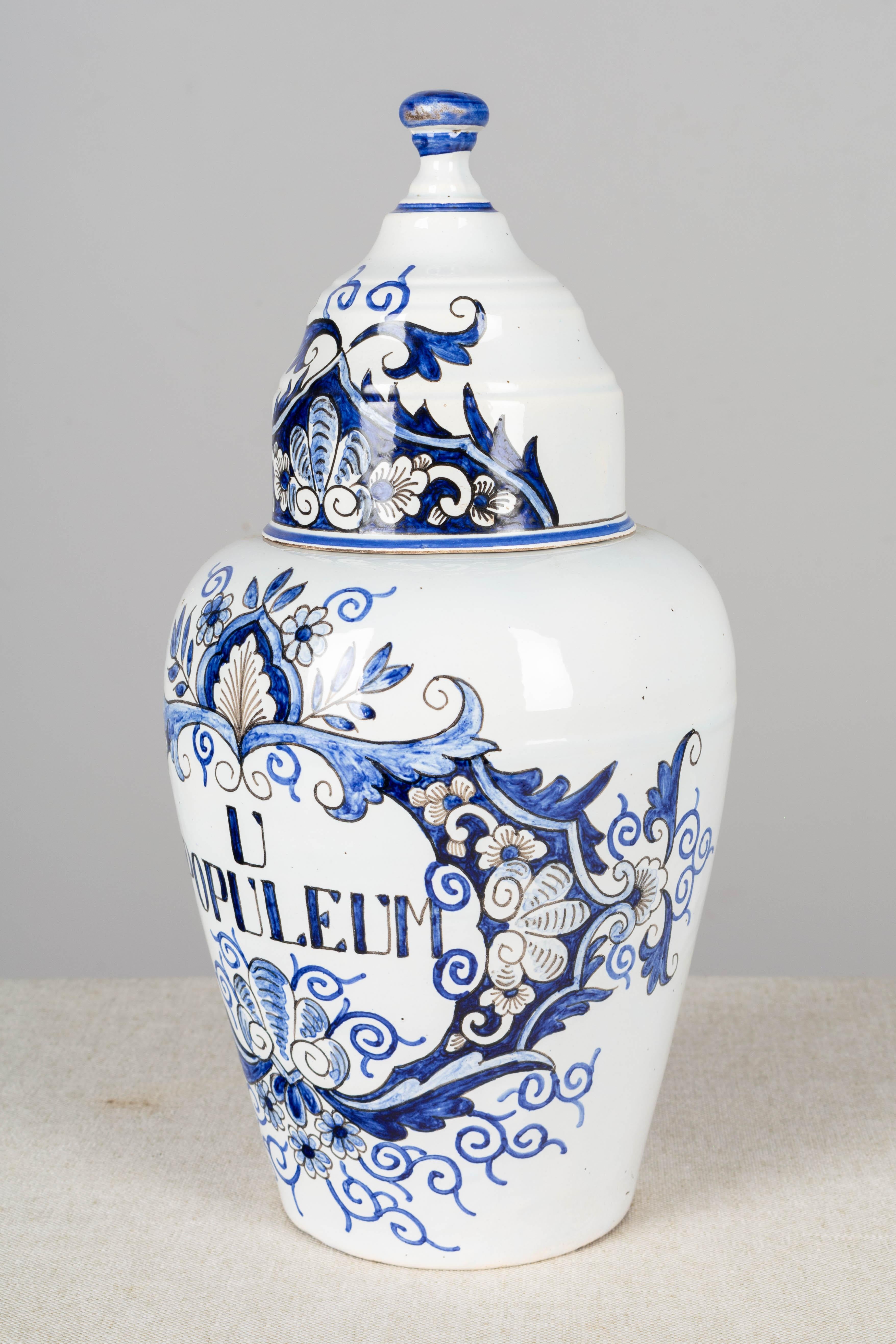 A delft faience apothecary jar, or pharmacy pot, with domed lid, blue hand painted decoration and label: U Populeum. Unmarked. Chip to rim of jar.