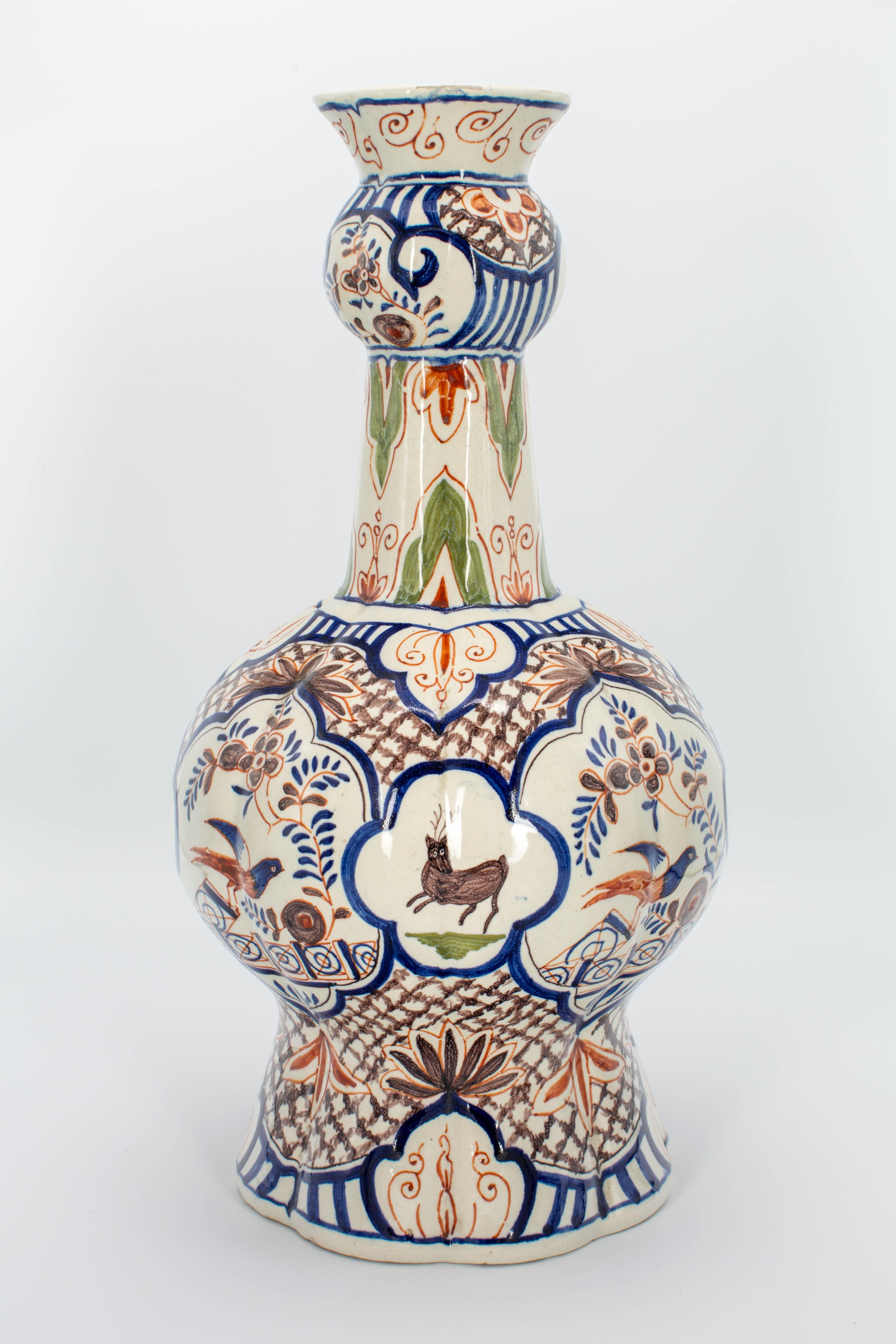 A 19th century delft faience polychrome painted vase with round body and narrow neck ending in an open bulb. Beautifully decorated in blue, orange, brown and green with large medallions framing nesting birds and reindeer. Weight: 5.6 lbs. Please