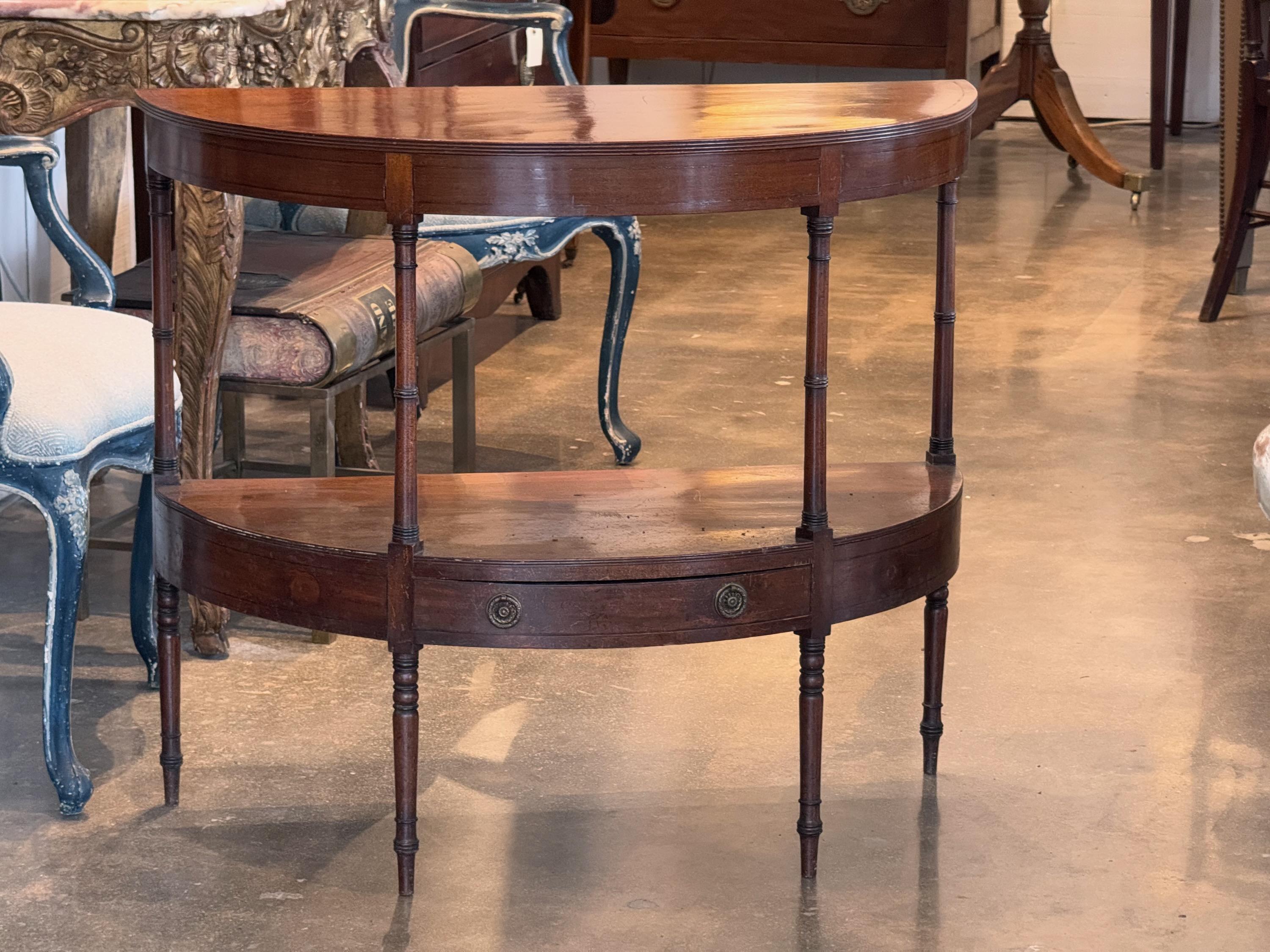A Demi lune console of mahogany wood. It has a drawer on the lower shelf.