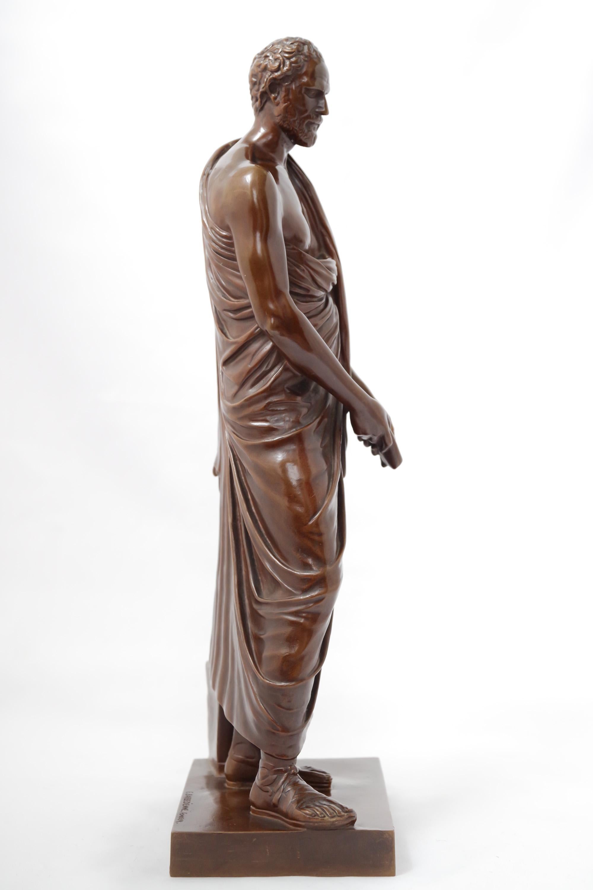 Figure en bronze représentant Démosthène (384-322 av. J.-C.), homme d'État et orateur grec. La sculpture est basée sur une copie romaine d'une statue grecque originale. La patine brun chocolat du personnage évoque immédiatement le travail de la