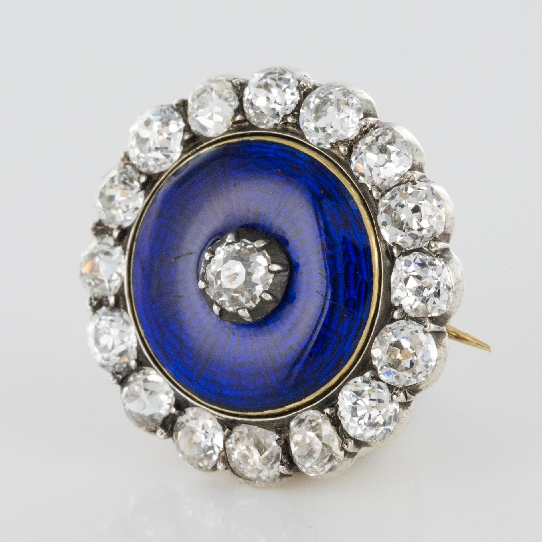 Brooch in 14 karats yellow and silver.
Lovely little antique round shape brooch, it is set with claws, in the center of a large blue enamelled decoration, of an antique cushion- cut diamond and surrounded by antique- cut diamonds. The clasp is a