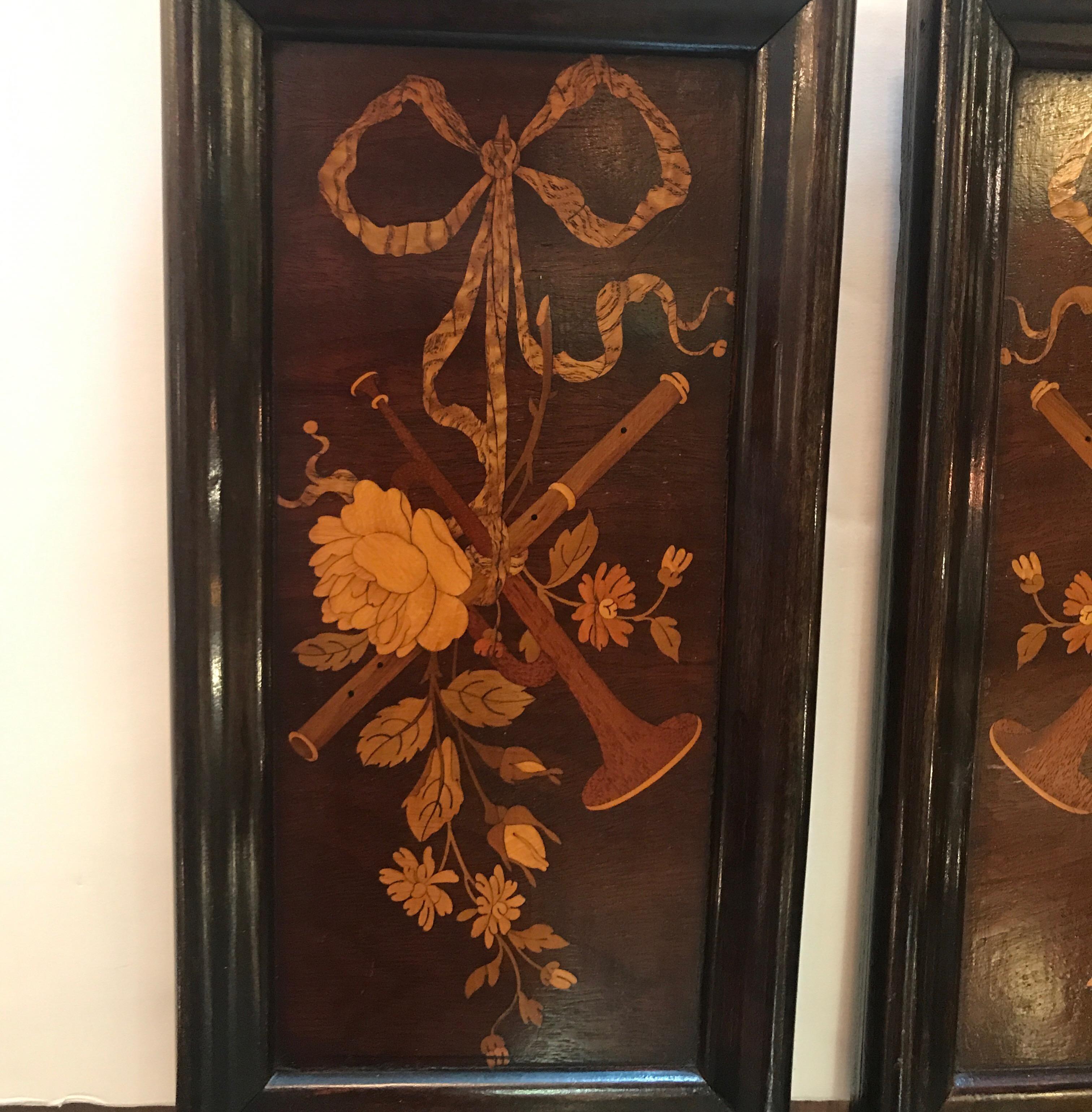 A pair of diminutive mahogany and satinwood inlaid framed panels. The wood panels with inlays of kings wood, tulip wood and satin wood with floral and instrumental motif each a mirror image of one another, a true original pair. Measures: 11 inches