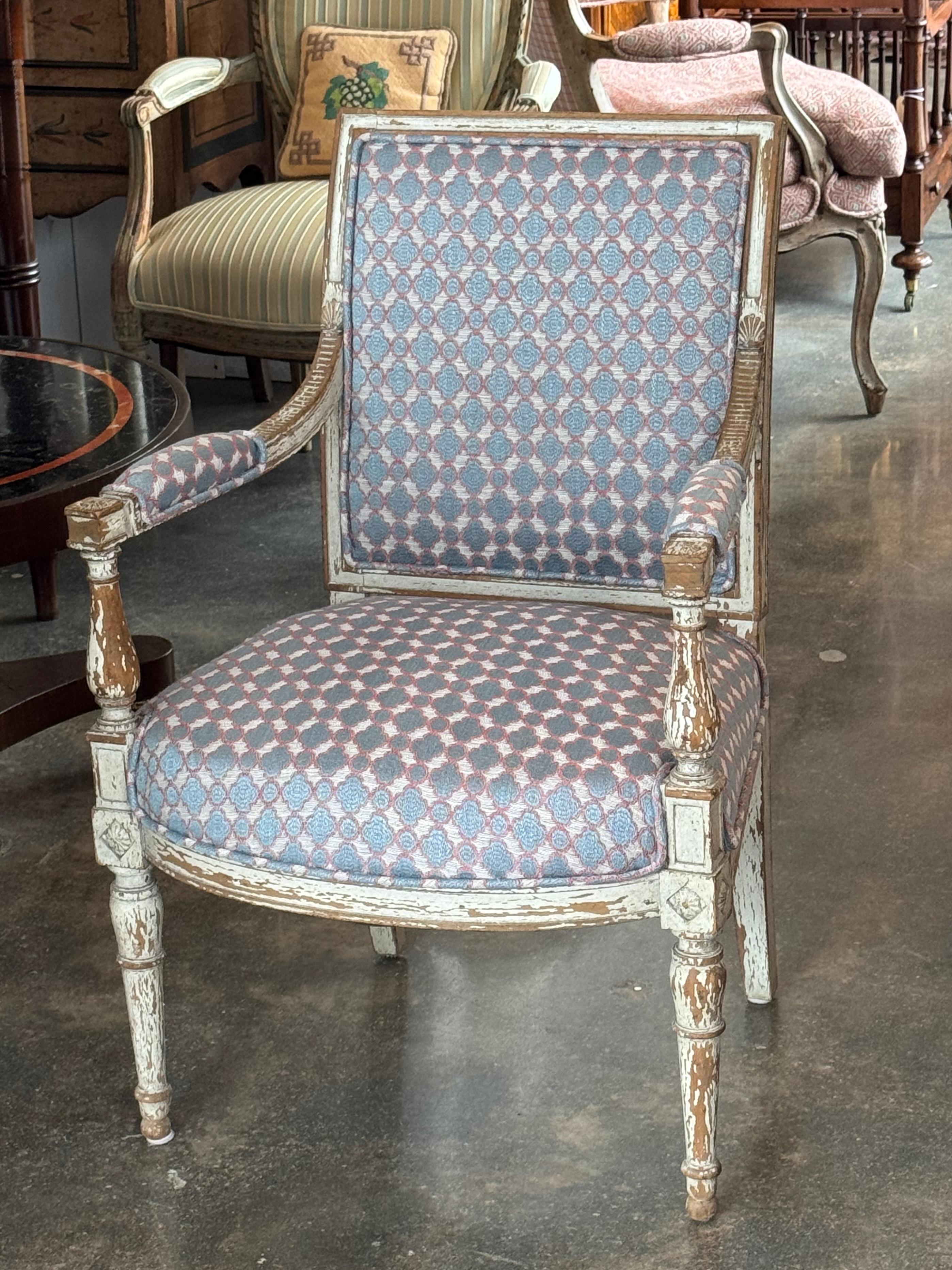 Sillón de estilo Directoire francés con armazón tallado y acabado pintado desgastado. El respaldo cuadrado y las patas estriadas reflejan la influencia neoclásica de la época, mientras que las rosetas talladas y los motivos de concha añaden detalles