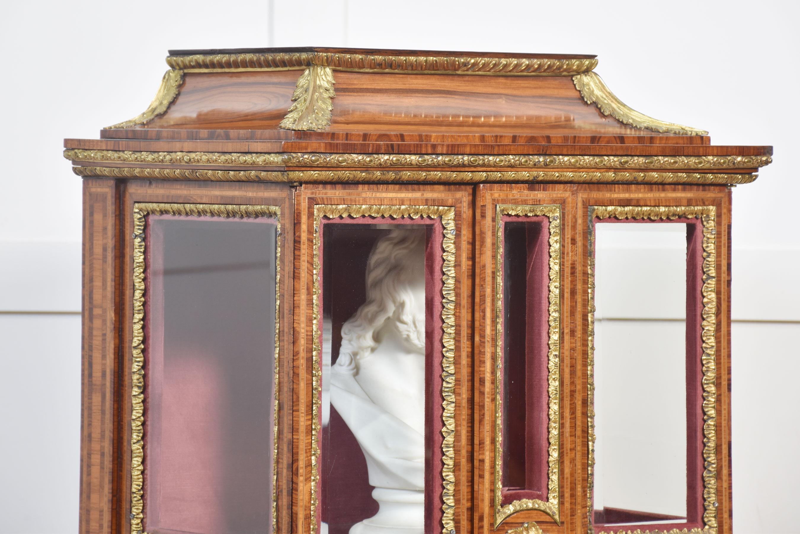 Display cabinet on stands the moulded pagoda-style top above bevelled glazed doors opening to reveal a velvet-lined interior and single glass shelf. The base section fitted with freeze drawer raised on four slender cabriole supports fitted with