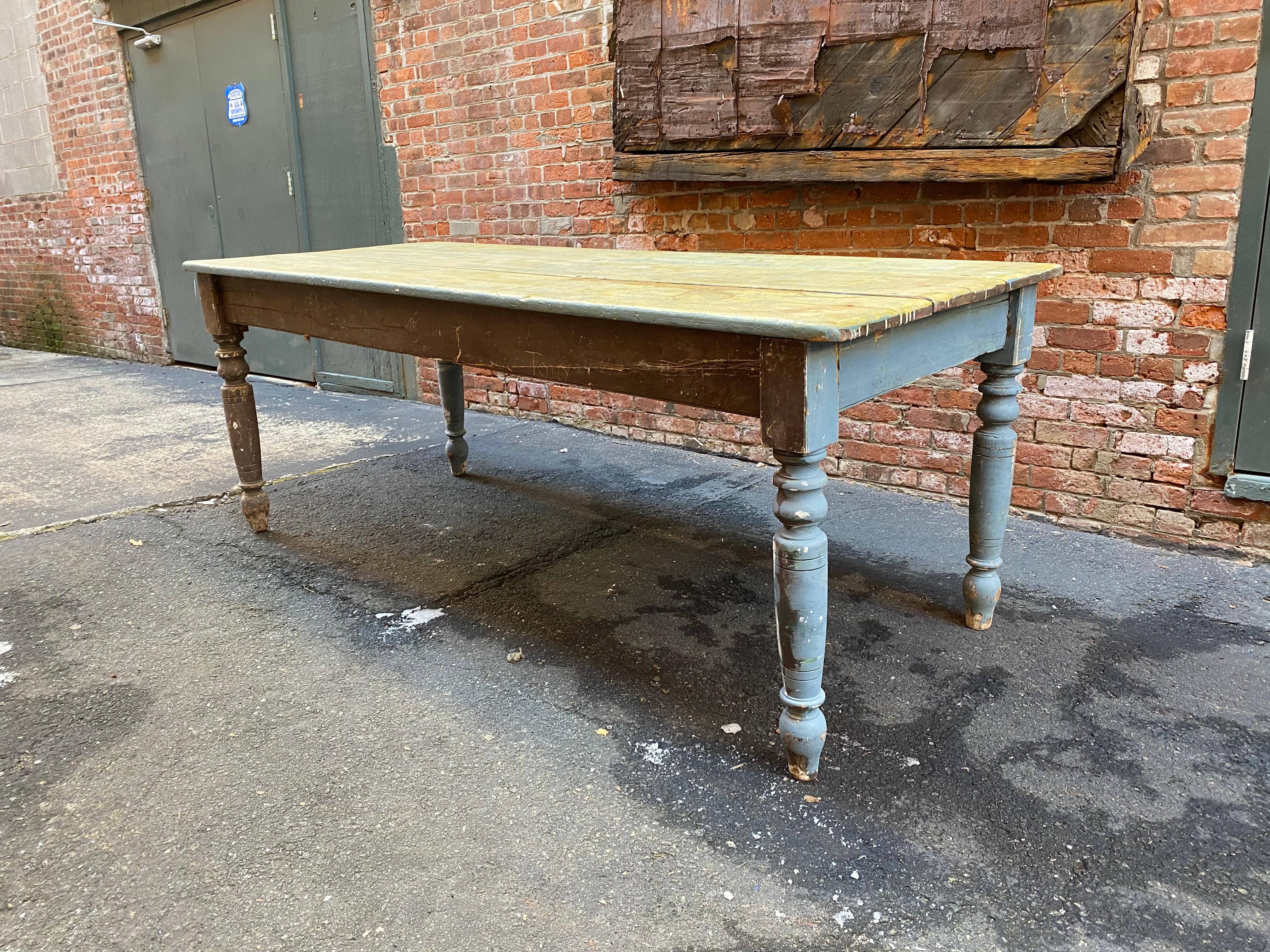 Painted and massive solid pine farm table with beautifully turned legs. Late 19th century farm table from a Rockland County, NY estate. Just the right amount of haphazard color of yellow, light cornflower blue and brown. Wide three board top that