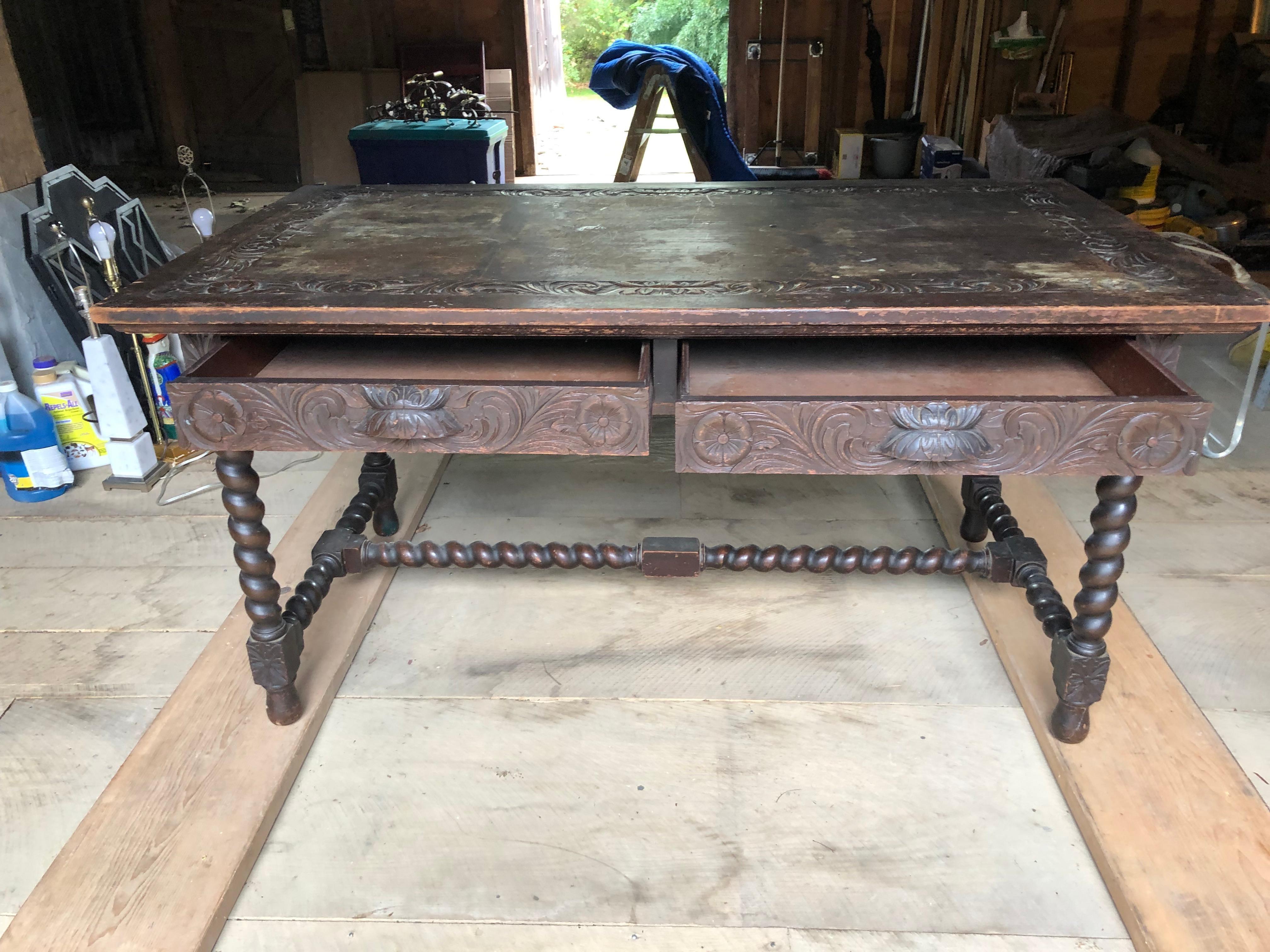 Rich in character early 19th century Spanish dining table or writing desk having beautiful carvings on the periphery of the top as well as the apron all the way around.  There are two drawers on the front, and handsome barley twist legs and