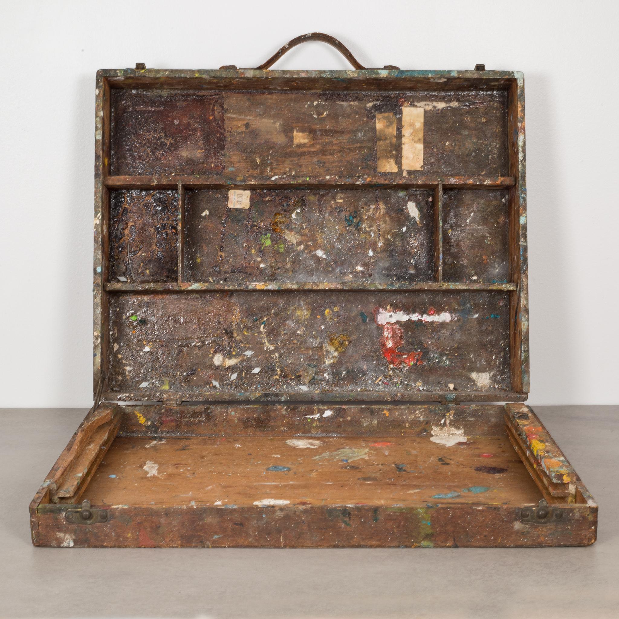 This is an original distressed wooden, artist's paint box with a leather handle and dovetail joints. The box has compartments for paint tubes and brushes with a hinged lid that partially opens in the front for easy access to brushes. This well used