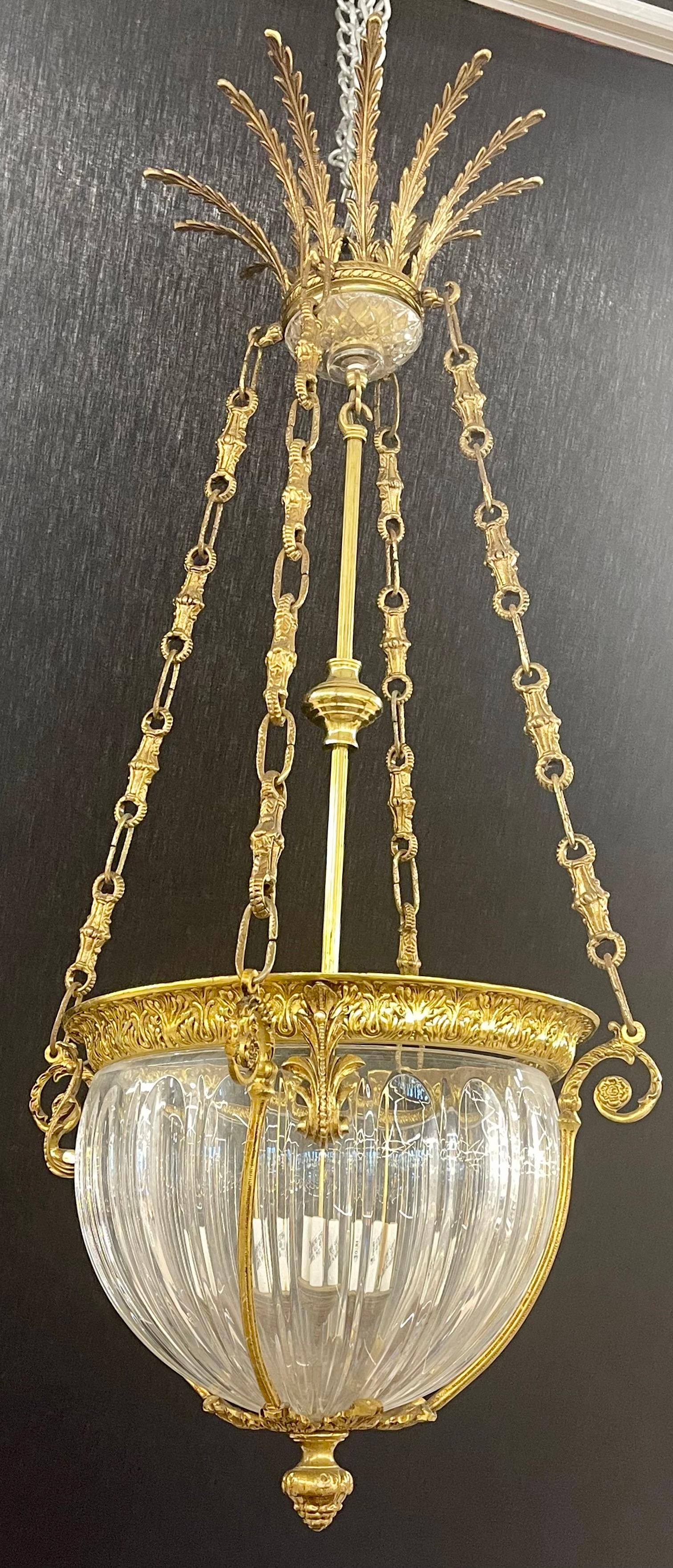 A gilt bronze chandelier having a decorative center crystal dome surrounded by Fine dore bronze decorative casting. The central column pole holding several lights suspended by three dore chains leading to a feather decorated canopy. Having four