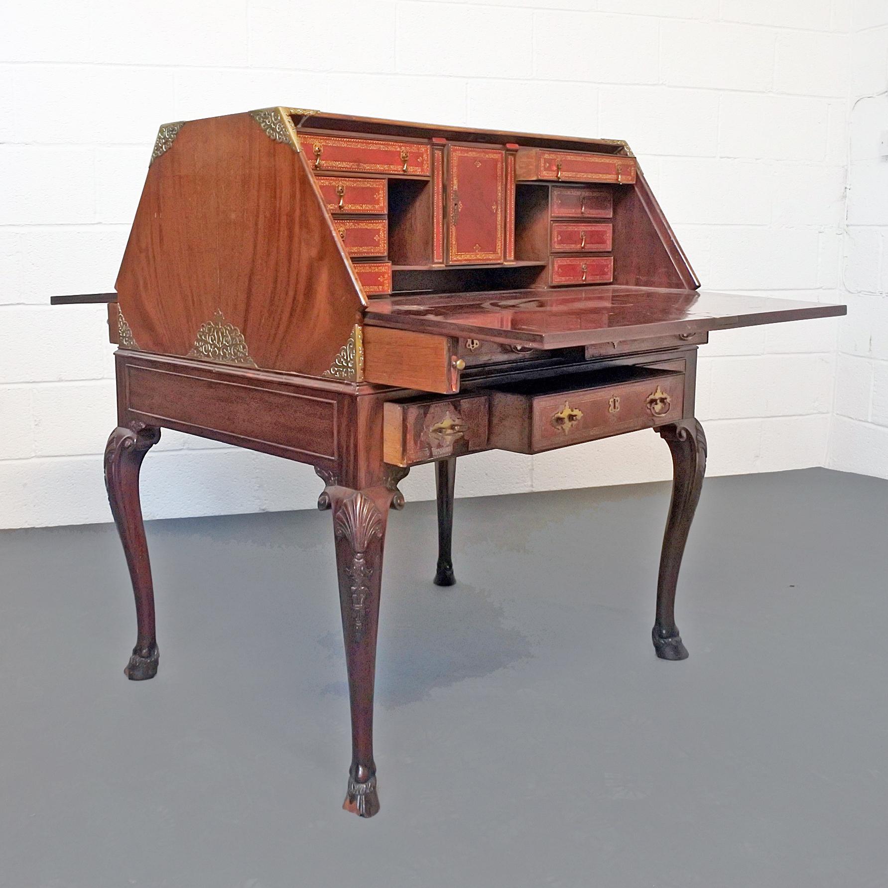 A 19th century double-sided bureau with leather fronted drop panels revealing intricately embossed leather fronted drawers and delicate brass fittings set on cabriole legs and hoof feet.