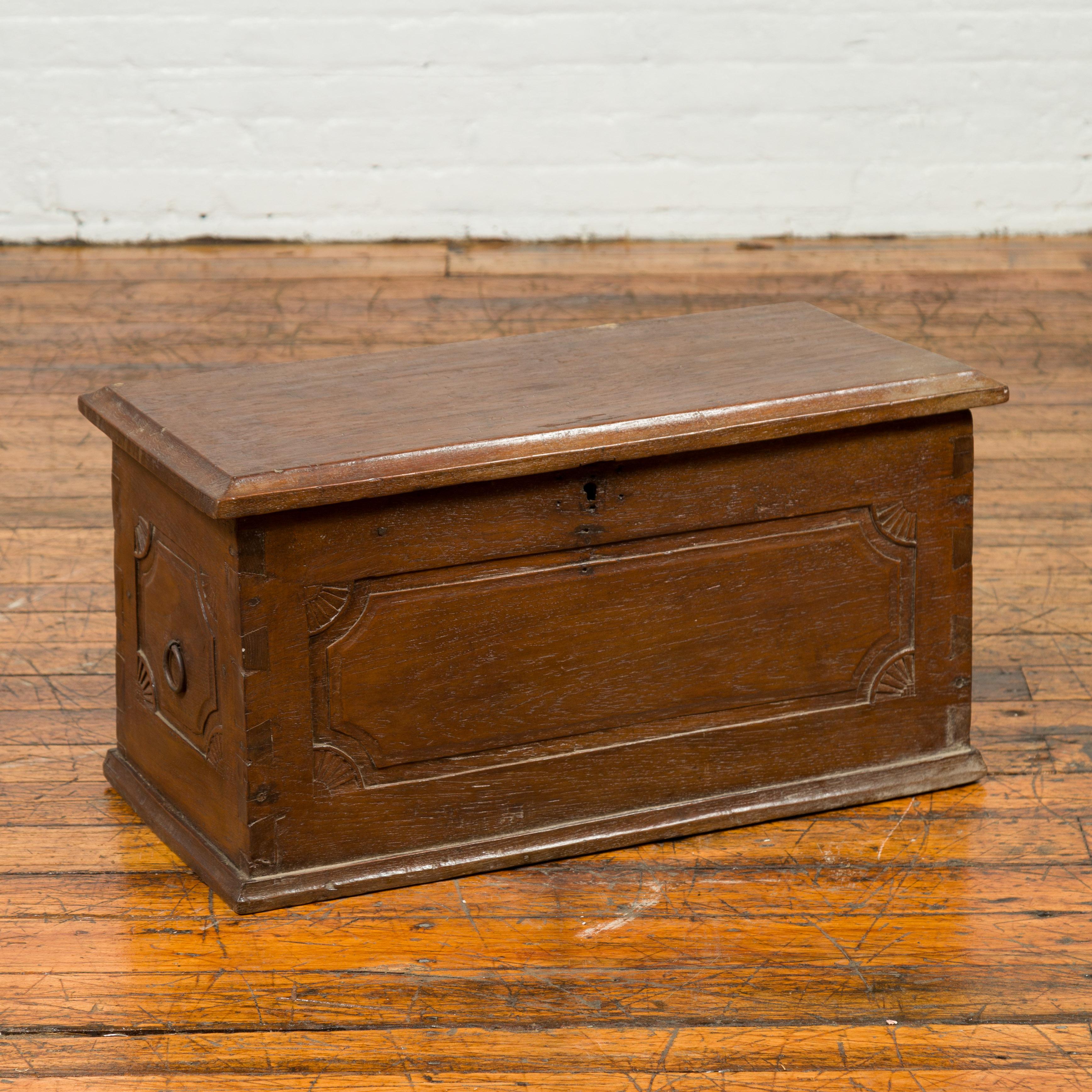 A 19th century Indonesian wooden treasure chest with carved fan motifs, dovetailed construction and lateral handles. Found in Sumatra, this wooden treasure chest features a rectangular lid with beveled edges, opening to reveal a storage space with