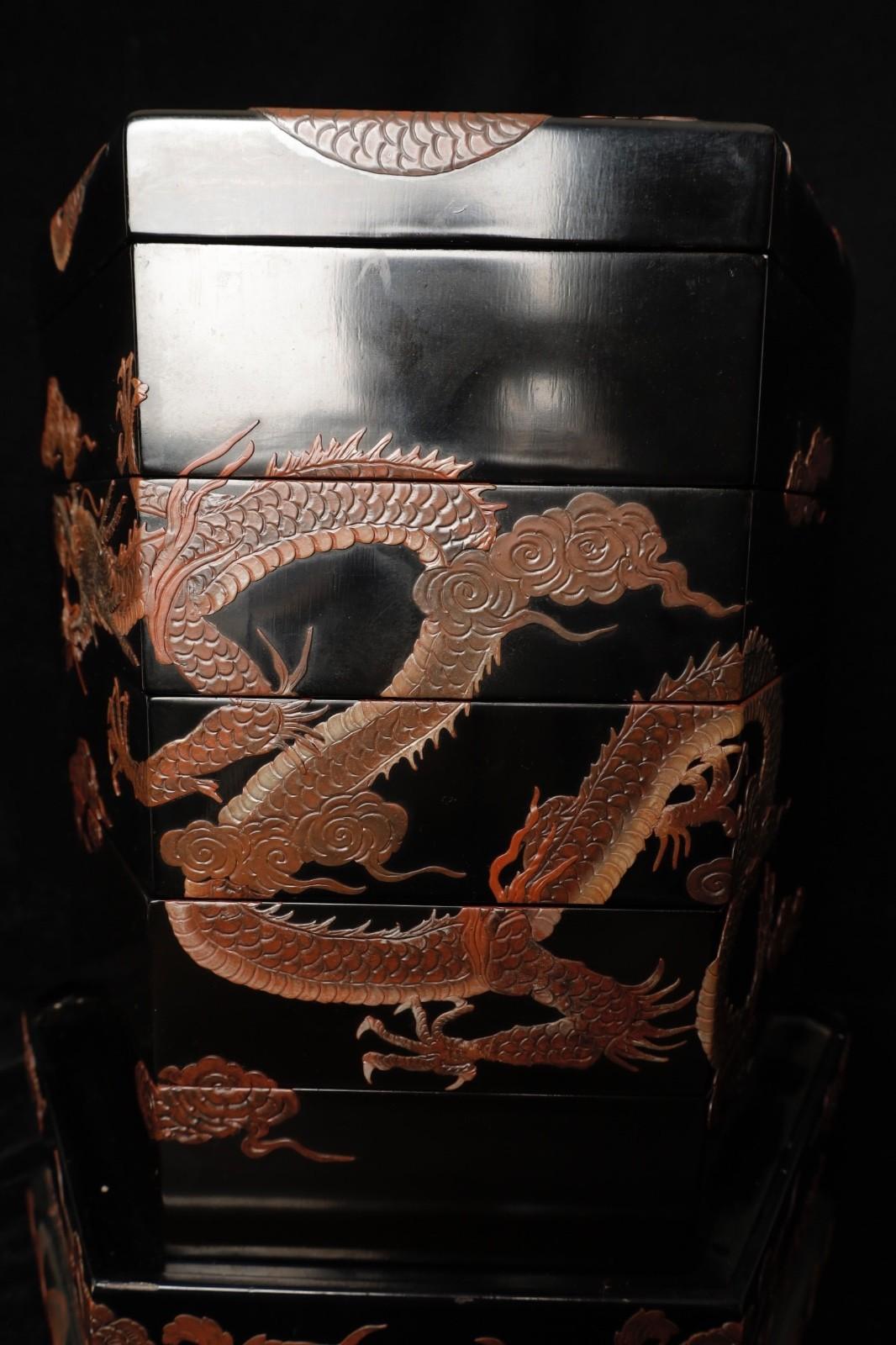 Gran caja hexagonal lacada sobre peana que representa a un Dragón volando en medio de  las nubes. La técnica única de lacado con apliques crea un efecto asombroso casi tridimensional. Lo más probable es que la caja de varias capas perteneciera a