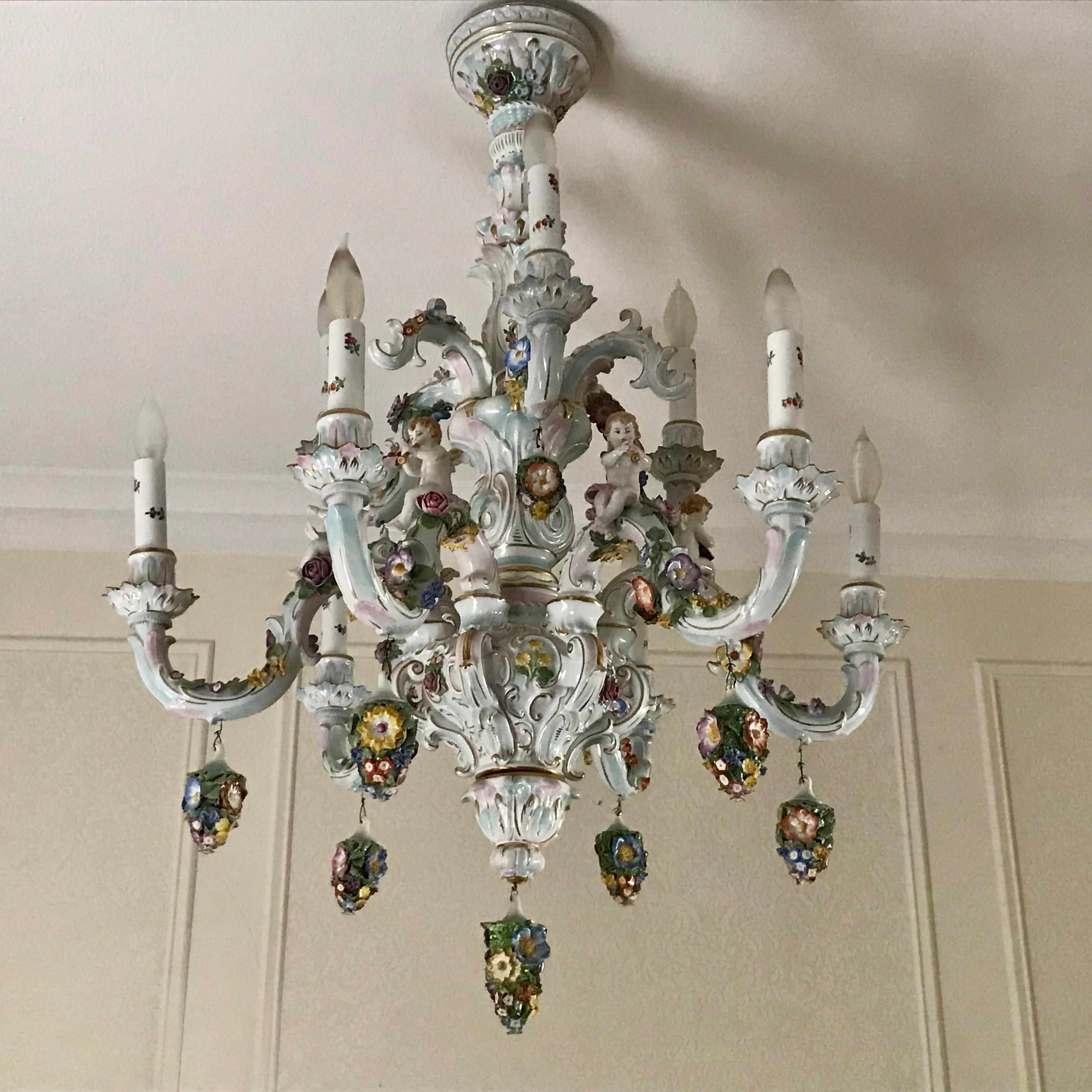 Superior quality and generous scale. The chandelier is fitted with 10 lights 
on its staggered arms - hand painted and appointed with florals, the chandelier
is fashioned with cherubs playing musical instruments in addition, the chandelier 
is