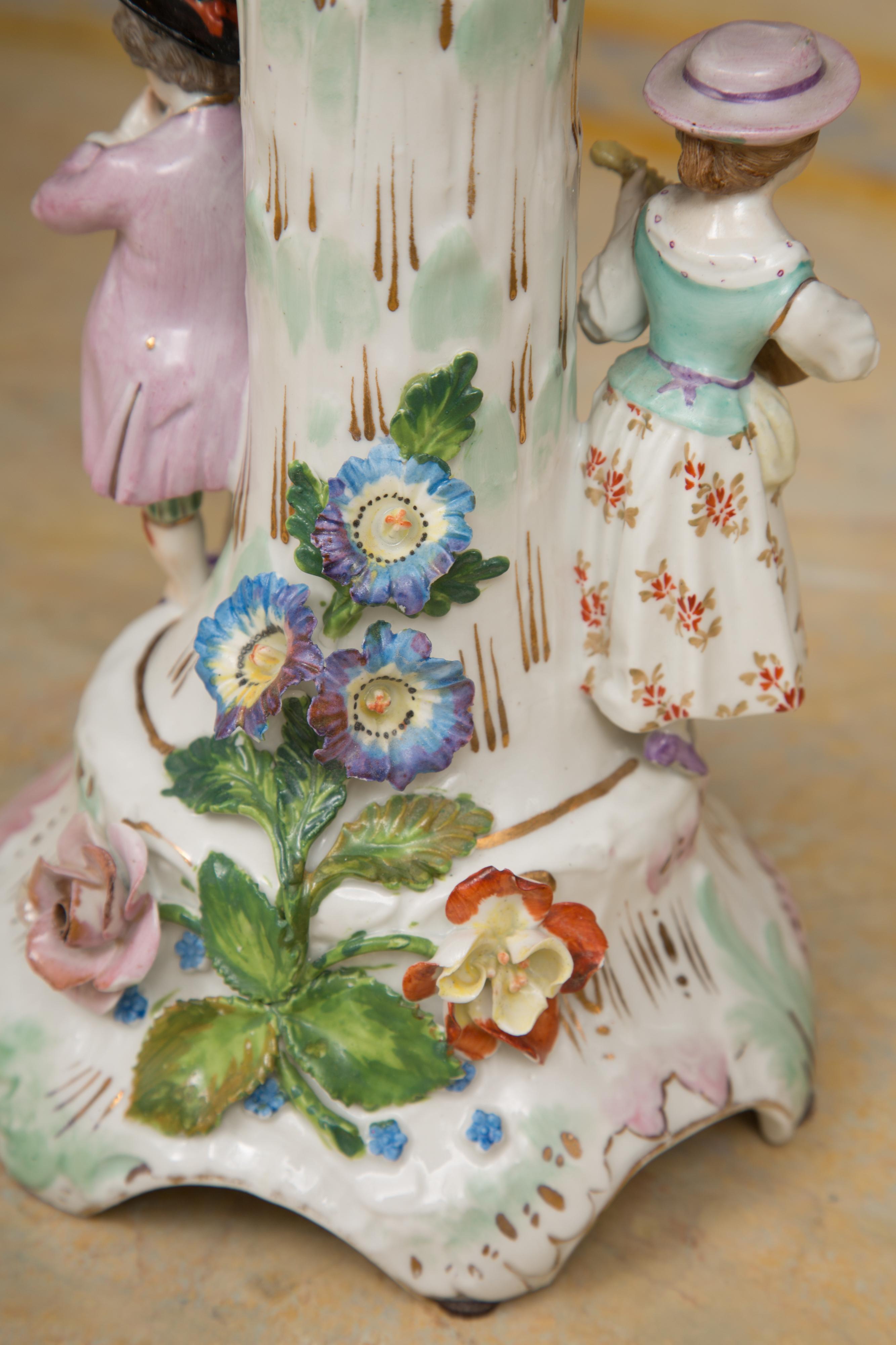 This is a beautiful Dresden Porcelain compote with a pierced square-form basket situated on a flower encrusted pedestal flanked by figures playing musical instruments, circa 19th century.