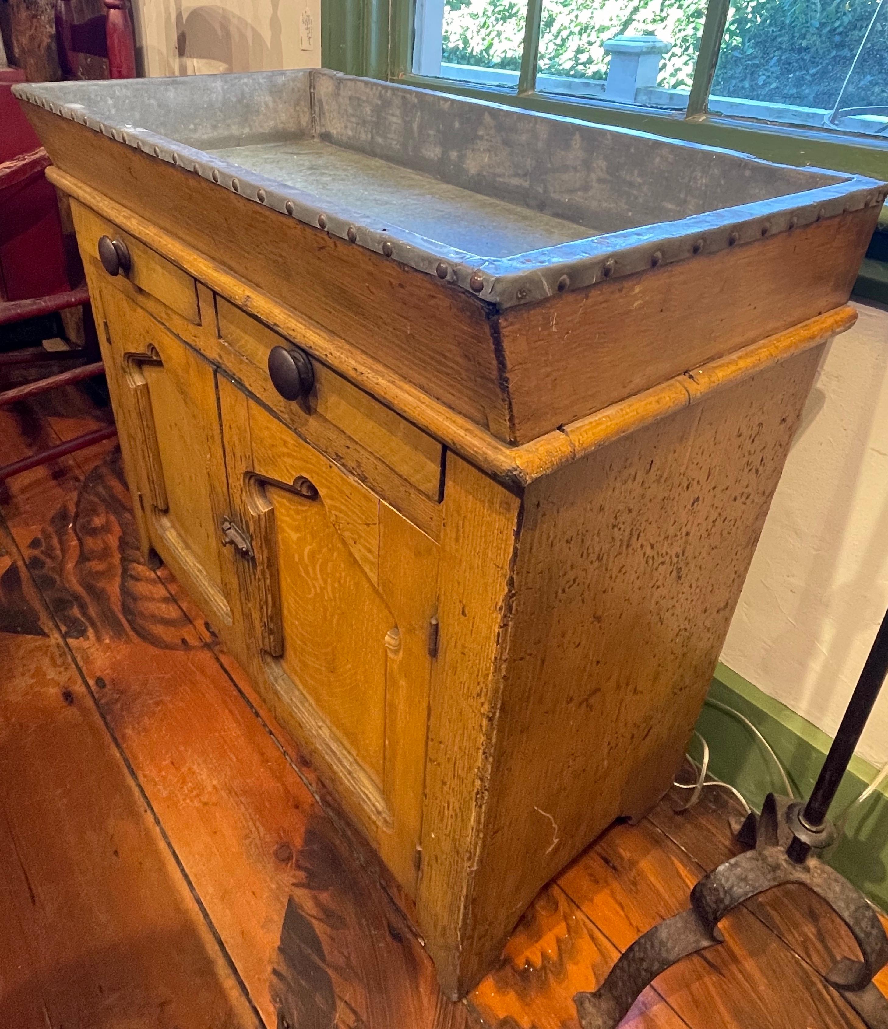 19th century Pine dry sink in original yellow vinegar paint. Inset zinc top above two drawers over two paneled doors. Interior with single shelf. Reverse unfinished.