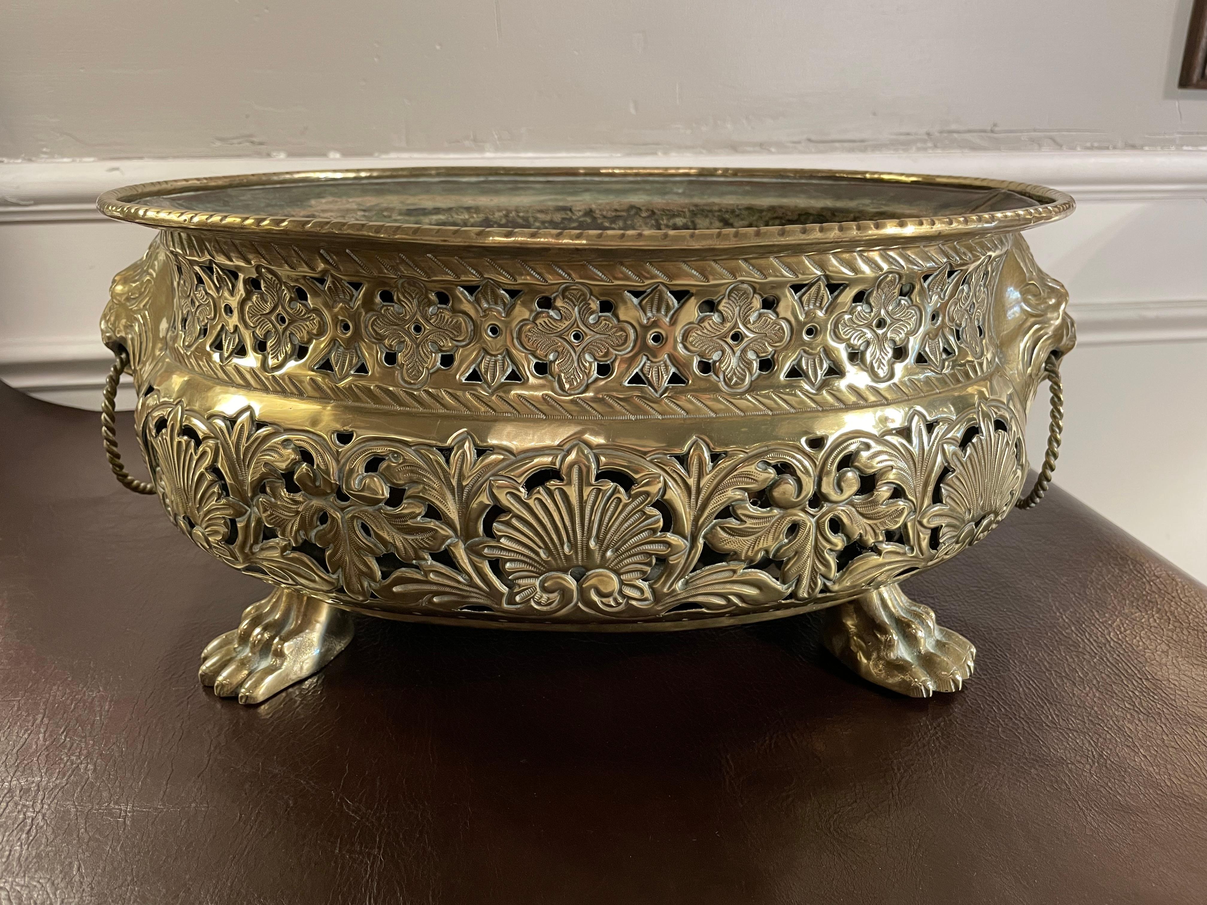 Dutch Baroque style brass table top planter or jardiniere with pierced fretwork and hammered repousse decoration of shell and floral motifs with gadrooned rim and borders. Wonderful applied lion heads on each end with twisted rope rings in their