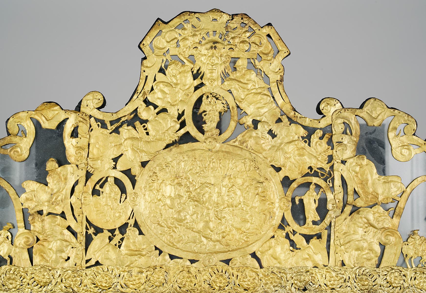 This 19th century Dutch Baroque style mirror features an ebonizes wood frame mounted with repousse gilt metal filigree overlay depicting leaf work, flowers, birds and traditional classical motifs. The raised designs were handcrafted using a