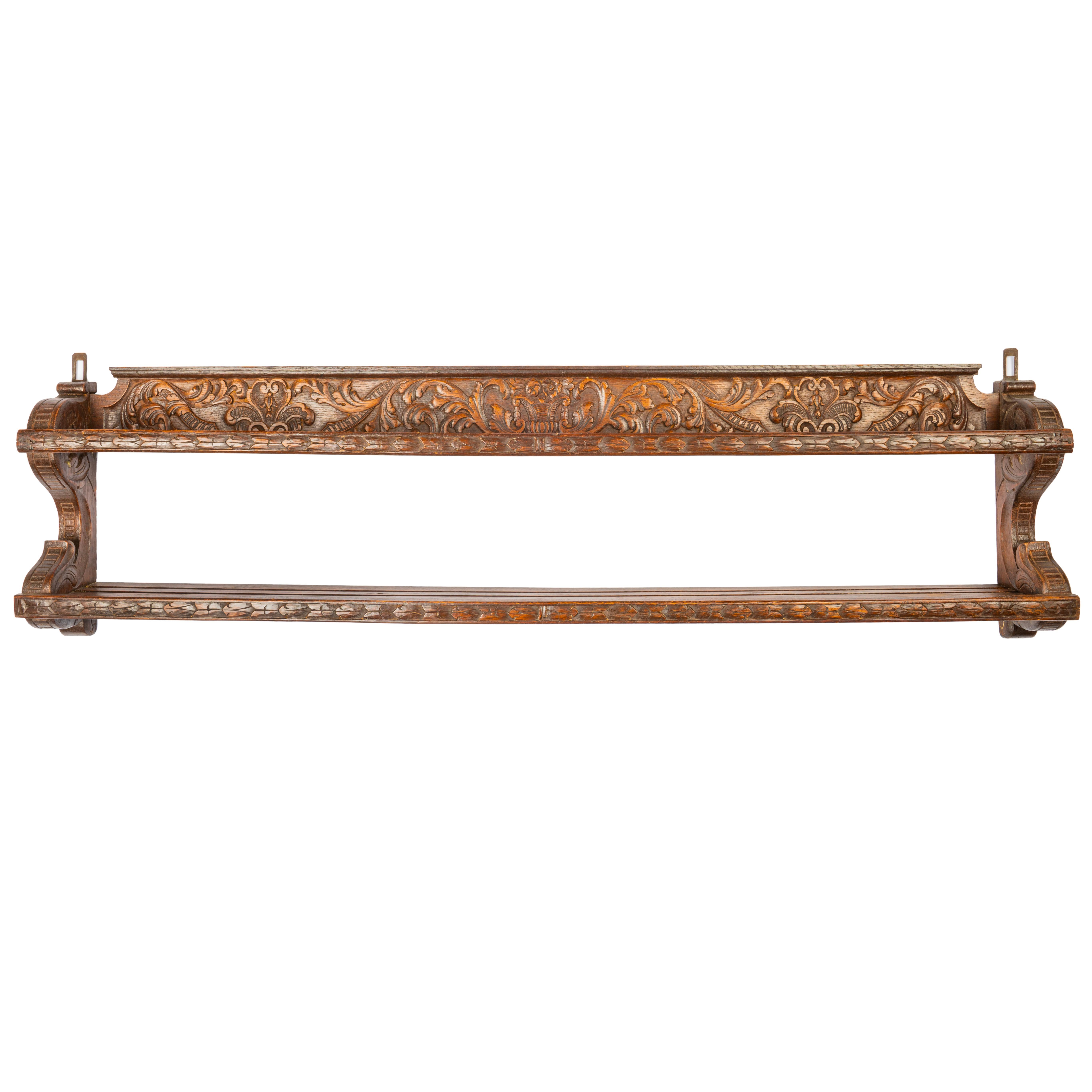 Distinctive Dutch plate rack of richly carved oak, designed for a single row of plates, the center of back board featuring a cornucopia, flanked by scrolling foliage and ribbons in the rococo style covering the entire length, the base rack with two