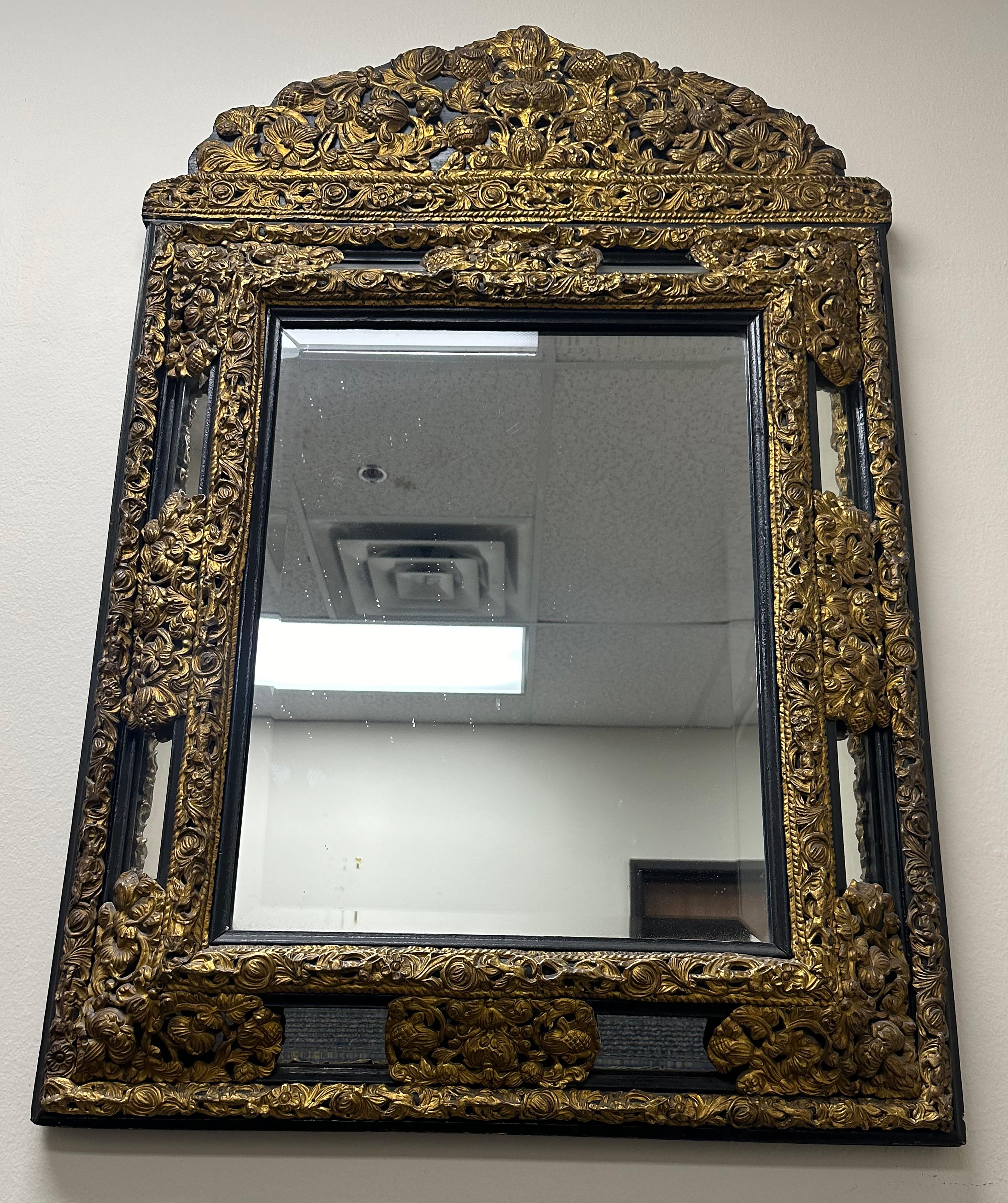 Dutch embossed brass and ebony mirror with floral motifs, beveled edge glass in the centre and 8 rectangular plates surrounding.