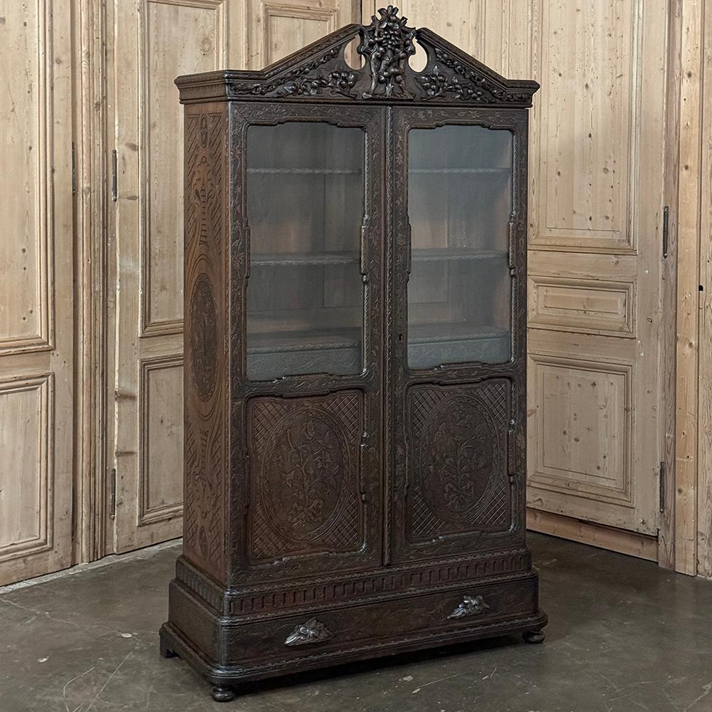 19th century Dutch Vitrine by Horrix is a study in the Dutch interpretation of the Regency style, hand-crafted from old-growth walnut with century old patina. Carved embellishment appears throughout the work from the crown centred with a robust