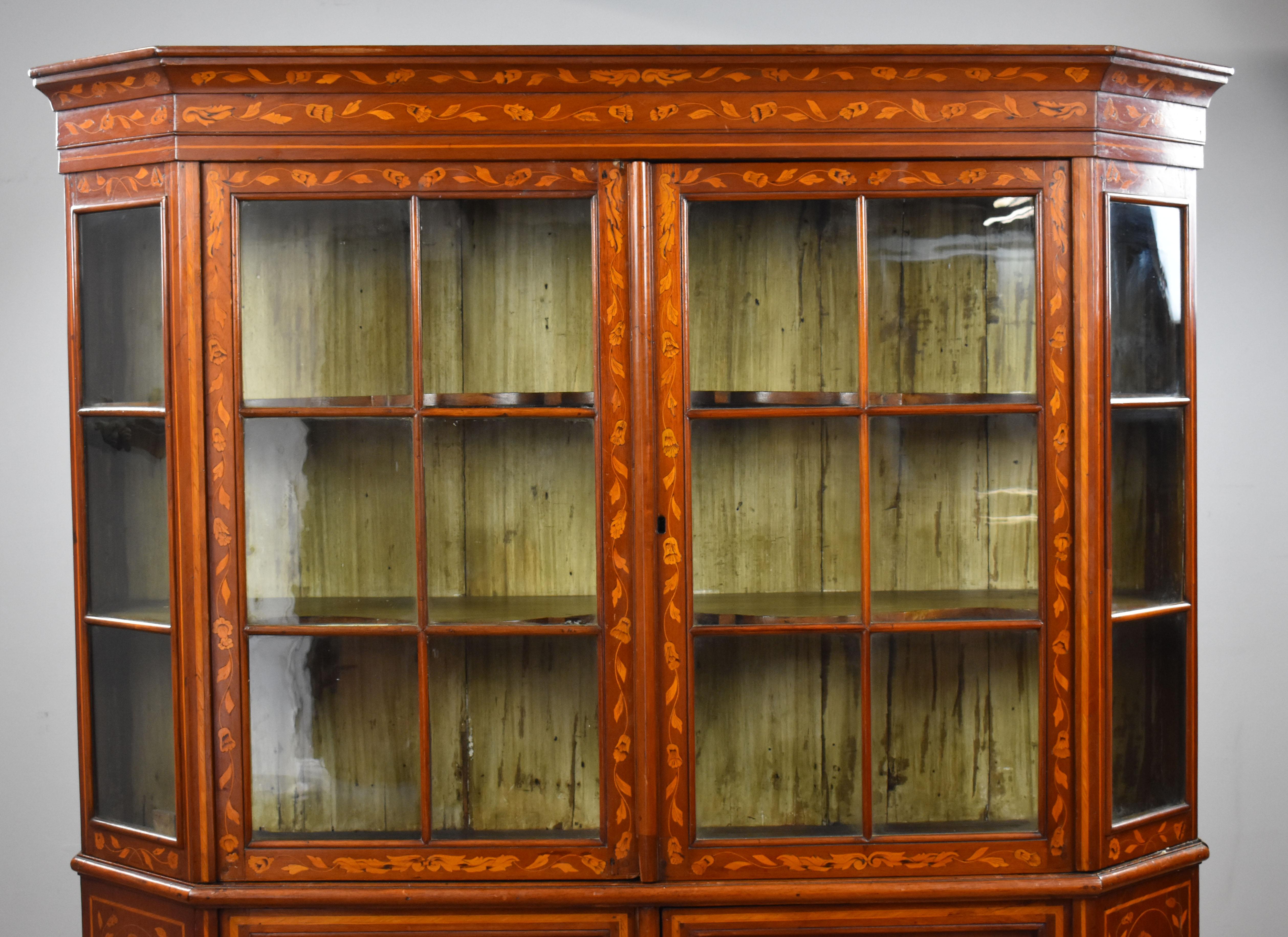 For sale is a 19th century walnut Dutch marquetry display cabinet, having two glazed doors enclosing shaped shelves, with two cupboard doors below, raised on bun feet. The cabinet is profusely inlaid throughout and is in good condition, showing