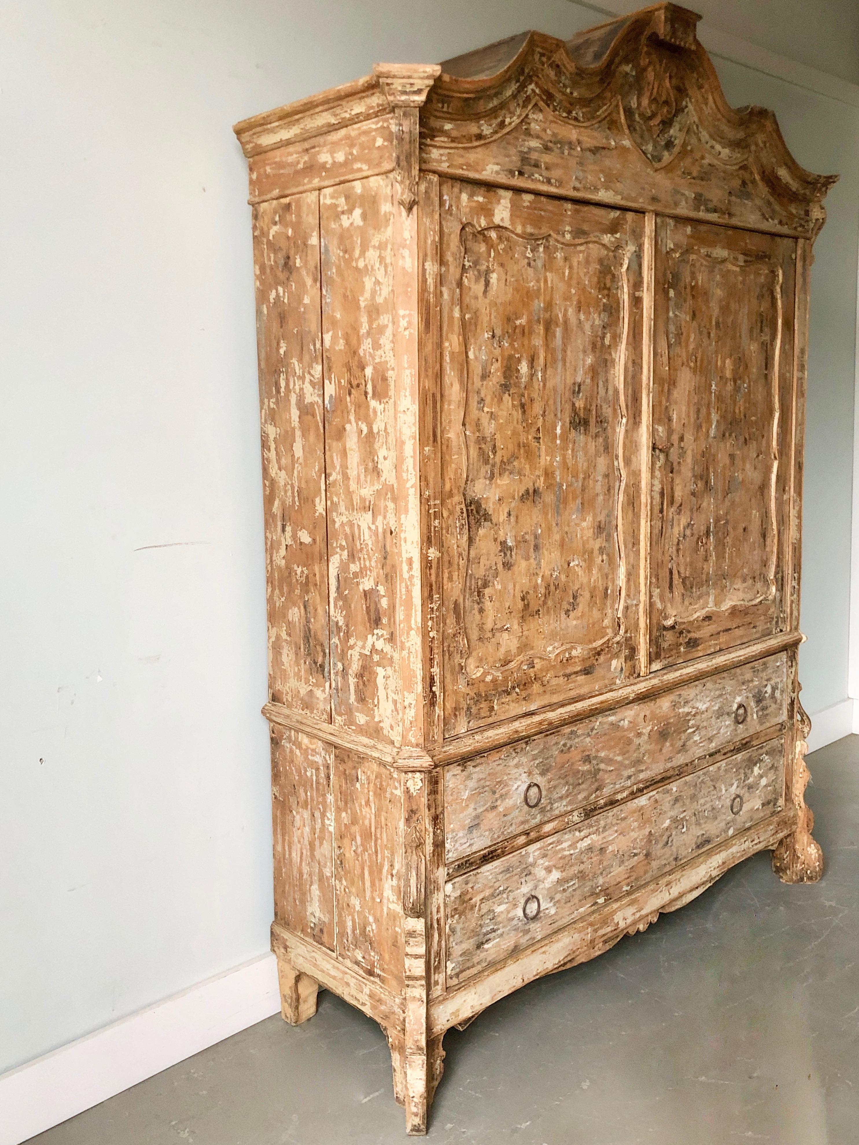 19th century Dutch oak cabinet in original worn patina with bonnet shaped pediment with delicate carvings and two large drawers with scalloped skirt and carved feet.

      