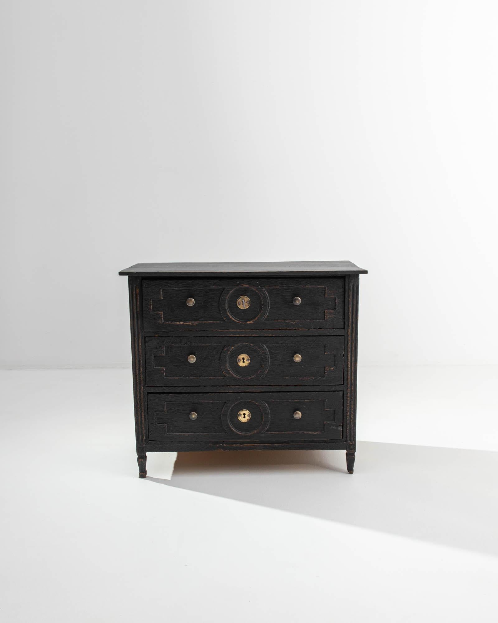 A wooden chest of drawers crafted in the Netherlands in the 19th century. Moody, yet crackling with an enigmatic energy, this chest of drawers is a picture of elegance and unique personality. The aged wood that composes its drawer fronts as well as