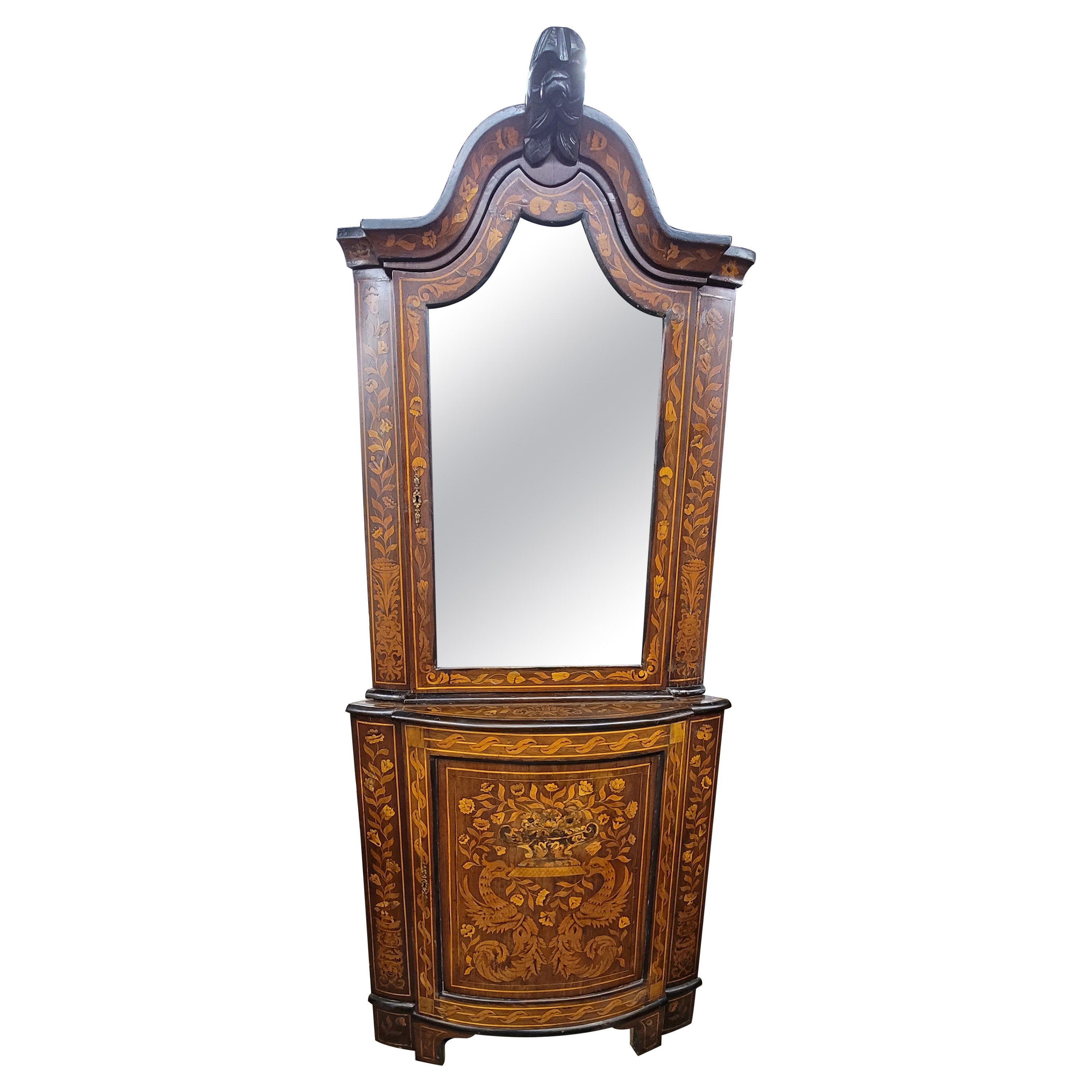 A dramatic Dutch colonial corner cupboard armoire with amazing marquetry work throughout the façade and featuring flowers, with birds, flowers, leaves and branches stemming from vases. Parcel ebonize base piece. Comes with original working lock and