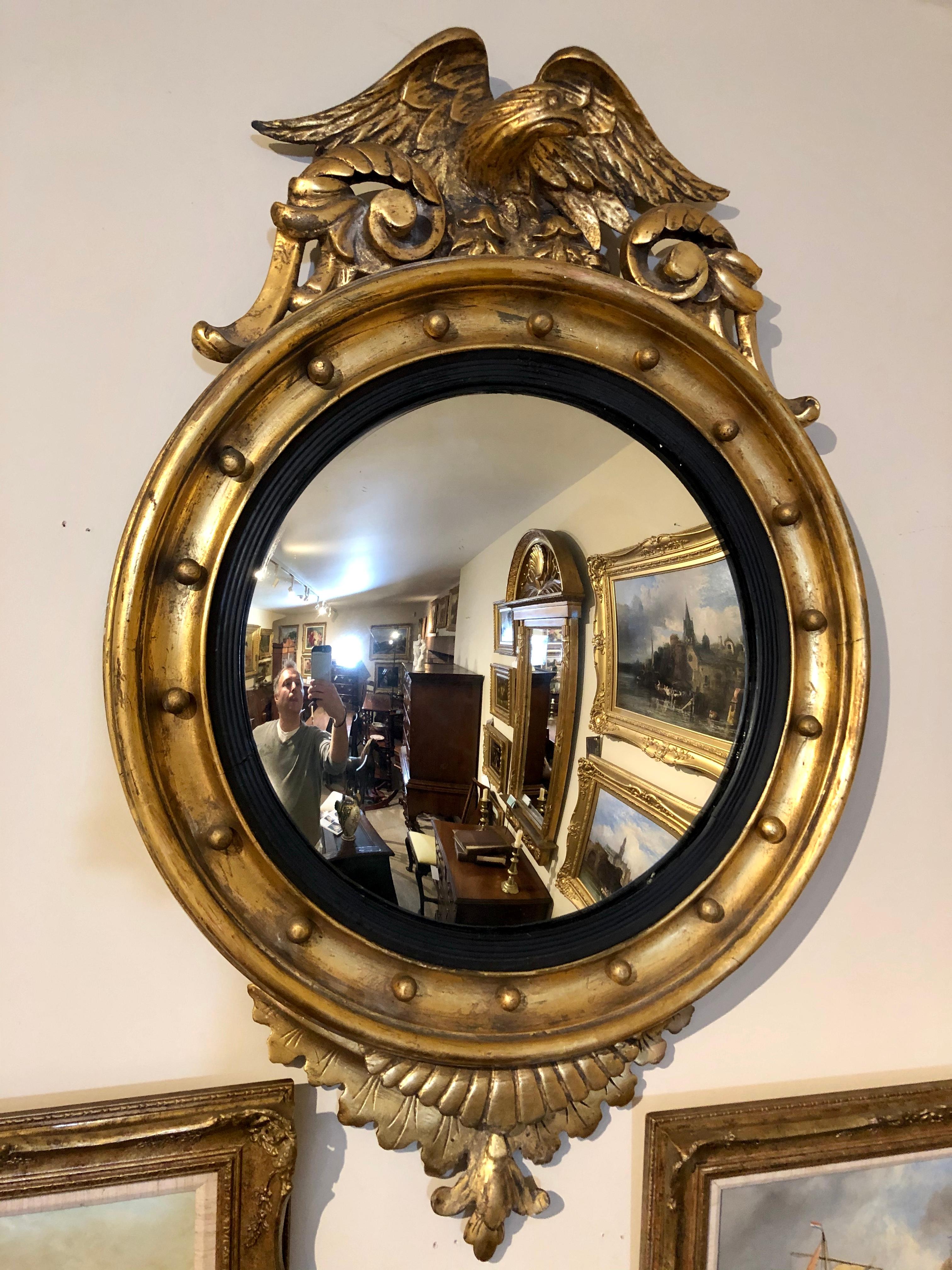 Good quality nicely proportioned 19th century English giltwood convex or bullseye wall mirror with an Eagle surmount and tail feather decoration to the underside. Ball shot decoration surrounds the gentle convex mirror. Original condition. A perfect