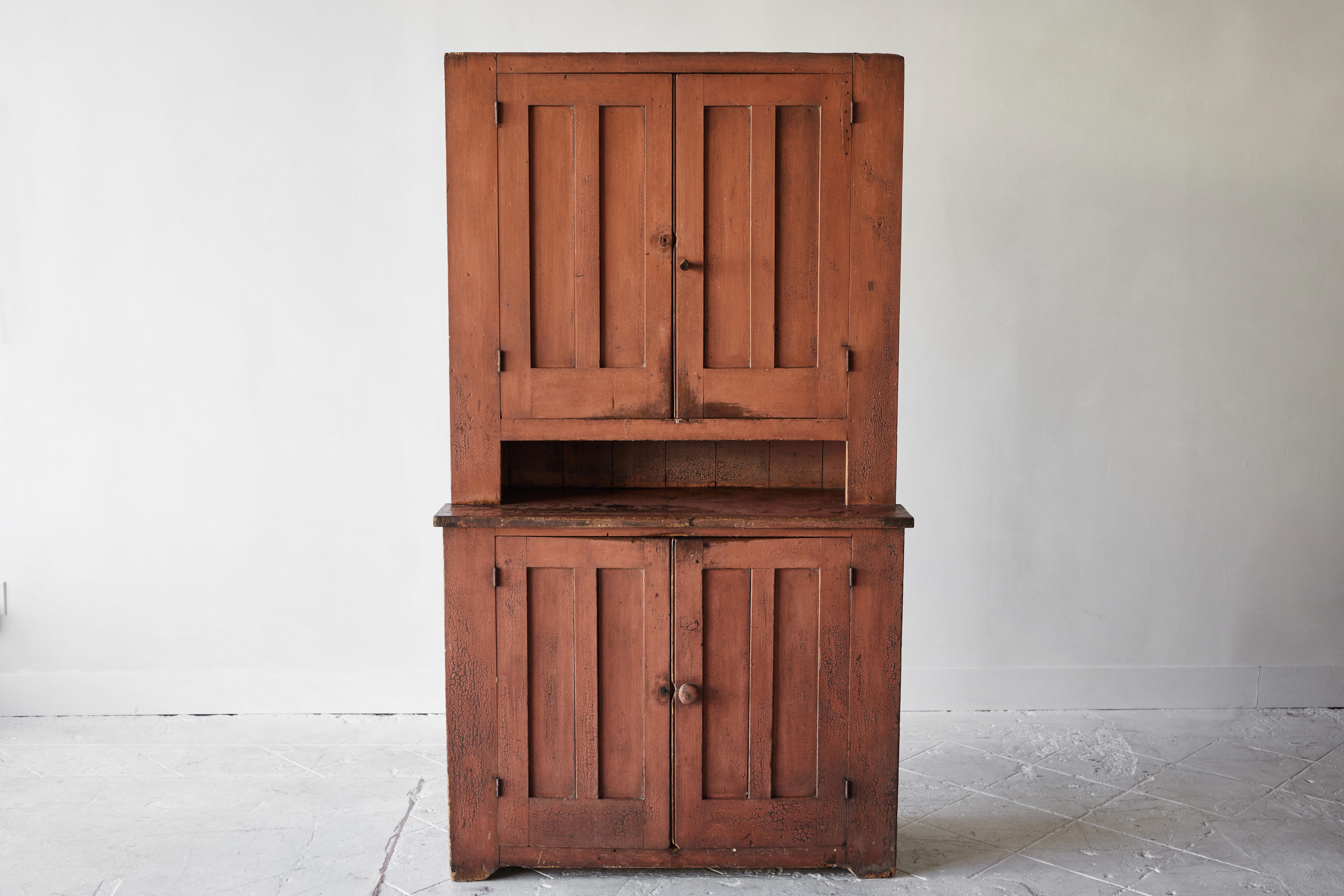 An attractive Early American four door cupboard with original paint. This cupboard is a wonderful utilitarian piece and features interior shelves allowing room for ample storage. The wood has a beautiful patina and the salmon color paint is correct