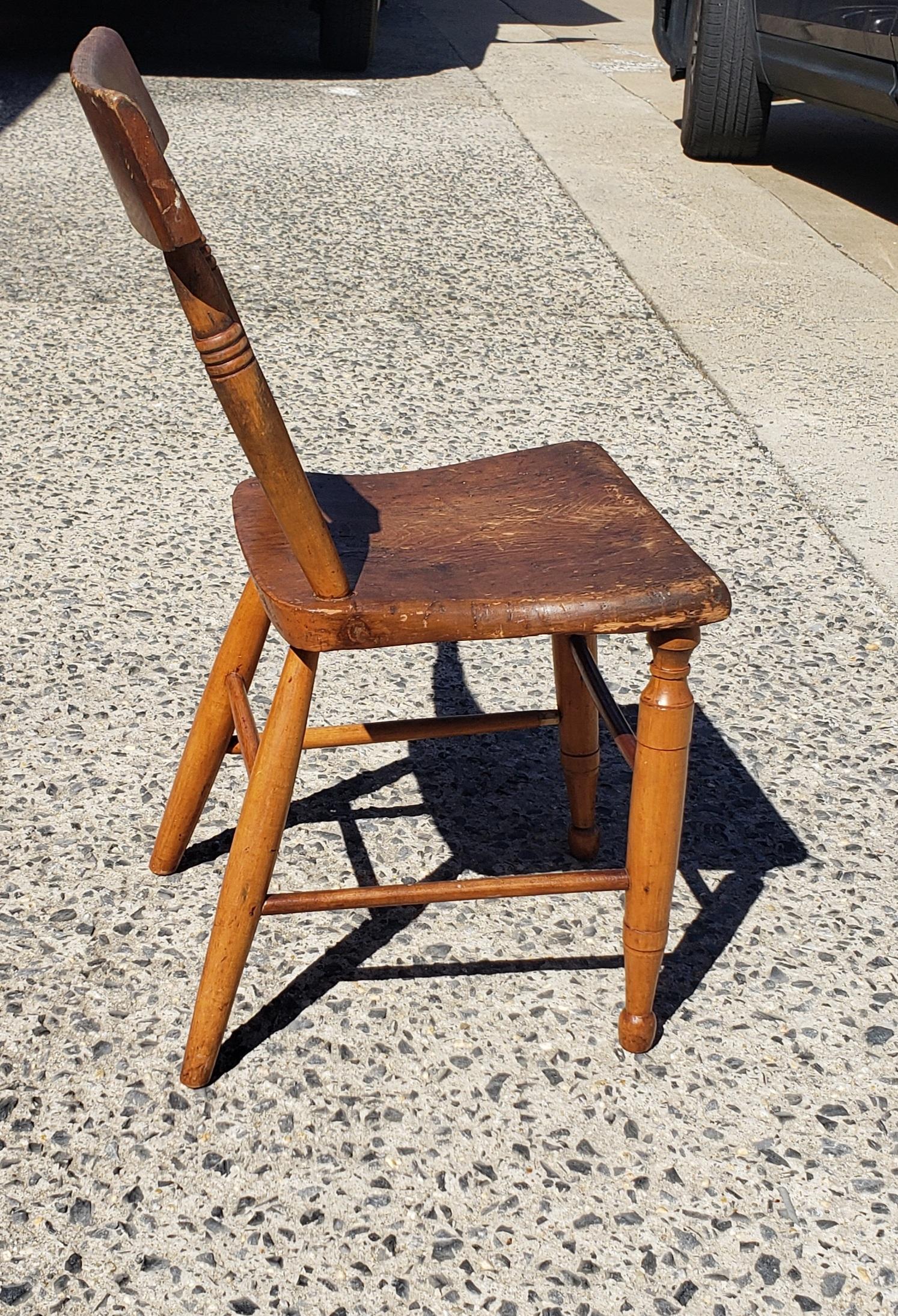 This is an antique primitive farmhouse chair circa late 19th century. The wooden chair features a plank seat with ladder back. Beautiful natural tone to the wood.