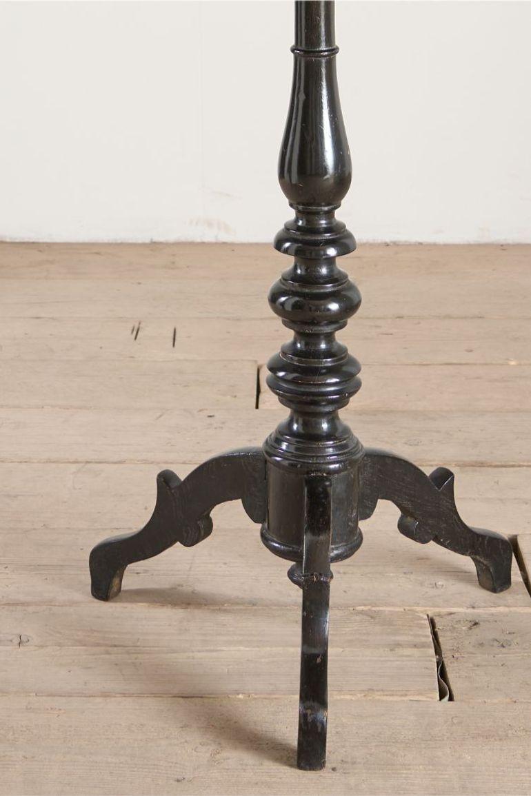 This is a very unusual occasional table that is 19th century in age with a striking ebonised turned base and highly decorated top. This gives the feel of masonic furniture and has CV painted into a crest. Overall condition is good with historic