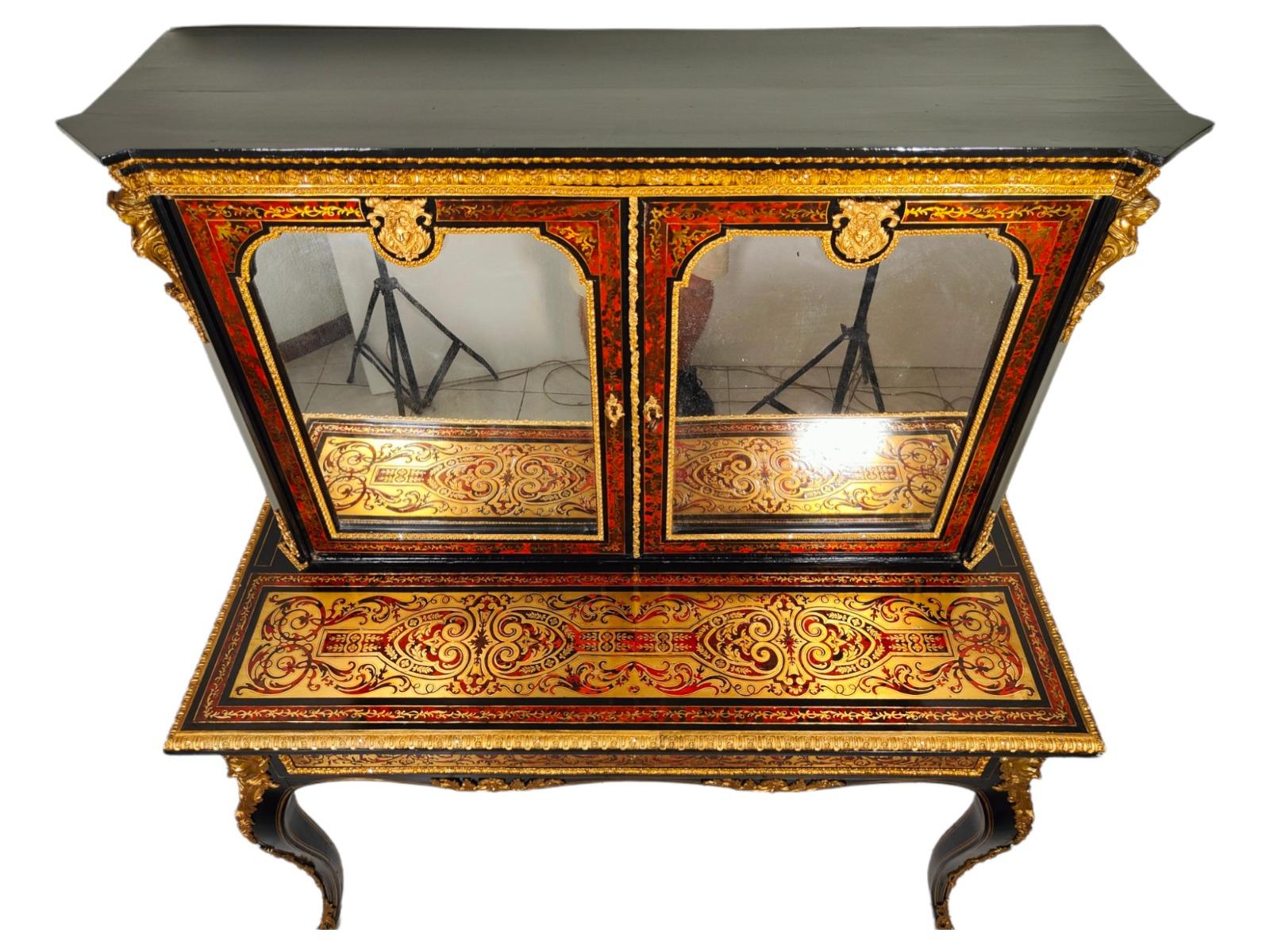 XIXth Century ebonised Boulle Bonheur Du Jour cabinet.The top has ornate brass mounts, flanked by brass gilded cariatides. Below this the two doors, each profusely inlaid with brass, open to reveal a polished interior with a single shelf. The
