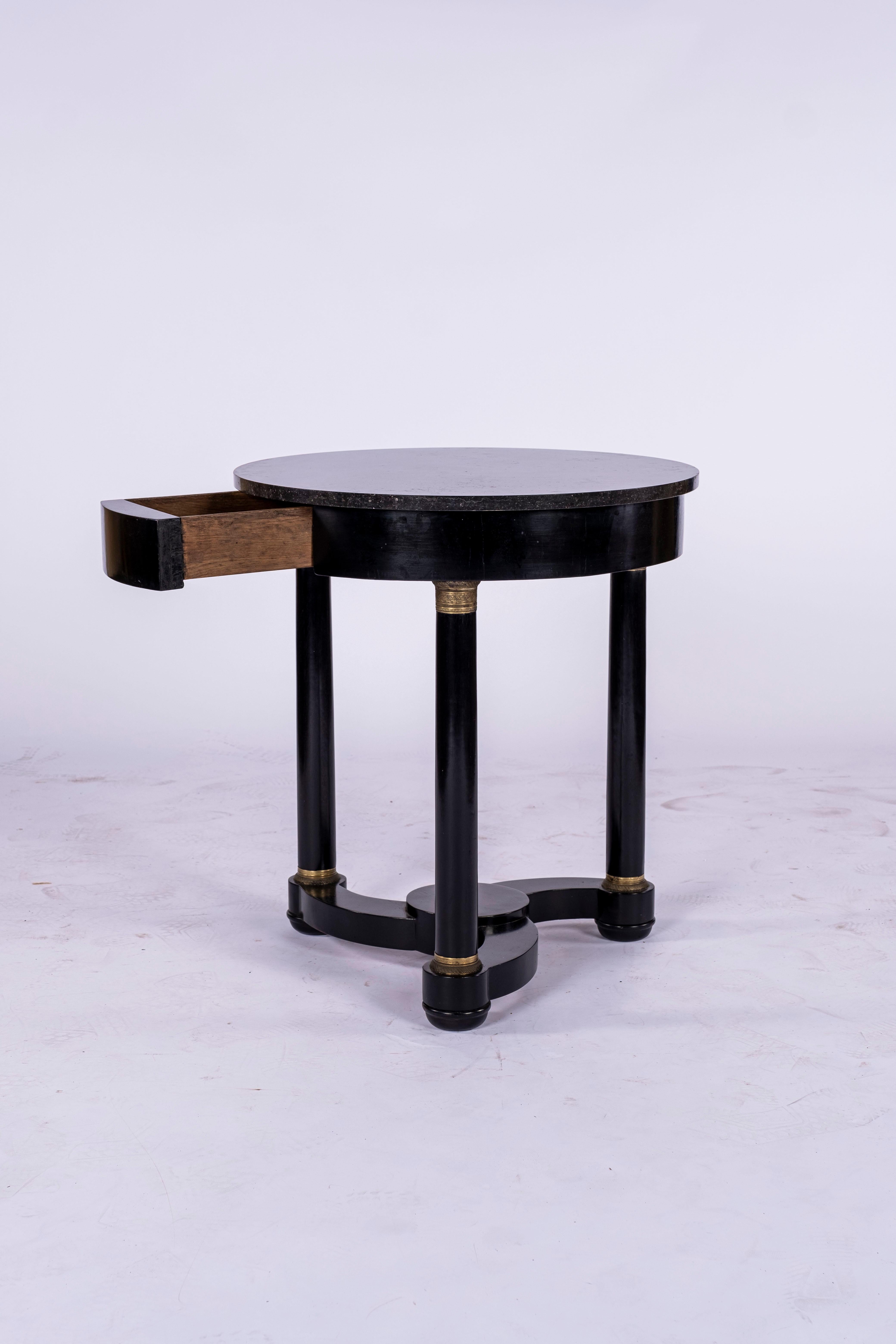 19th century ebonised Gueridon with a single drawer. Table has its original Belgian Black Marble Top and three cylindrical legs linked together by a propeller base. Decorative gilt bronze detail at the top and bottom of each leg. Found in France.