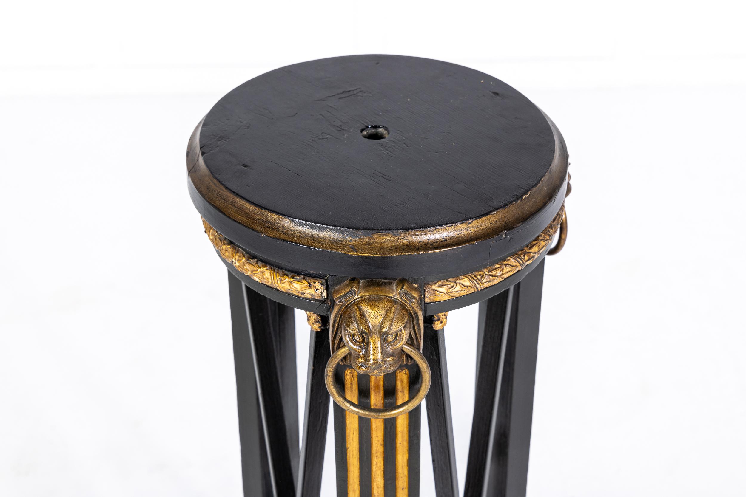 An interesting gilt metal and ebonised torchère or stand in the manner of Thomas Hope, English c.1910

The torchère of triangular form but with a circular top, mounted throughout with gilt metal including the finely cast feet, the lion mask handles