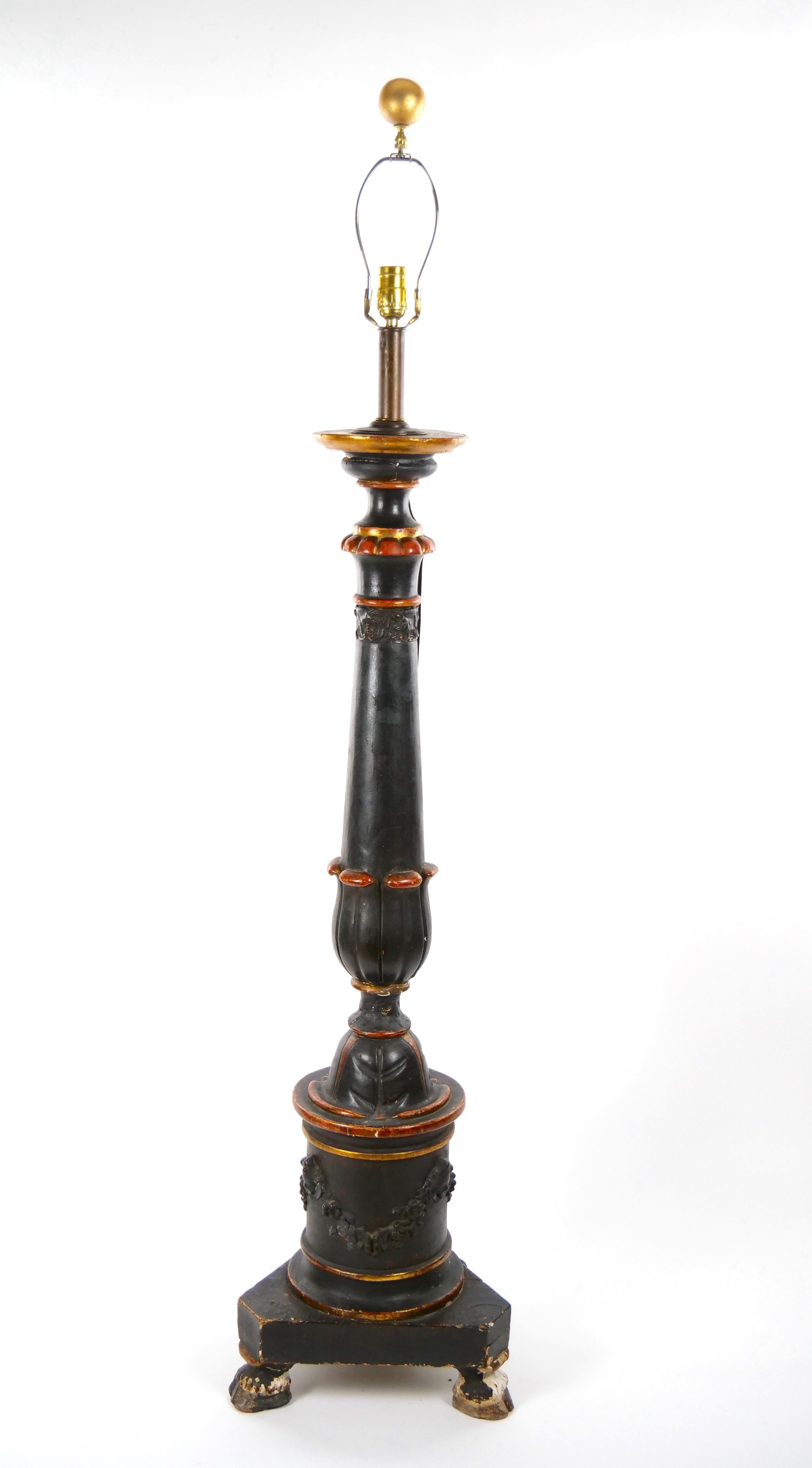 Antique carved and turned wooden floor lamp with triangular base with ebonized and hand-painted finish, plus finely carved motifs including stylized foliate designs, floral swags and animal hoof feet.  With new brass hardware and shade with