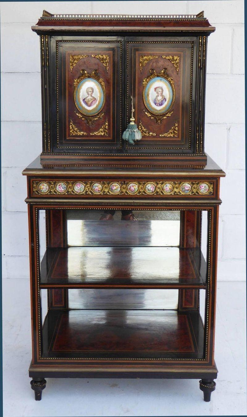 For sale is a 19th century amboyna and ebony cabinet, with three quarter balustrade gallery, above two panelled doors set with Paris porcelain portrait panels upon a two tier open Stand with gilt metal mounts and a porcelain panelled frieze. Below