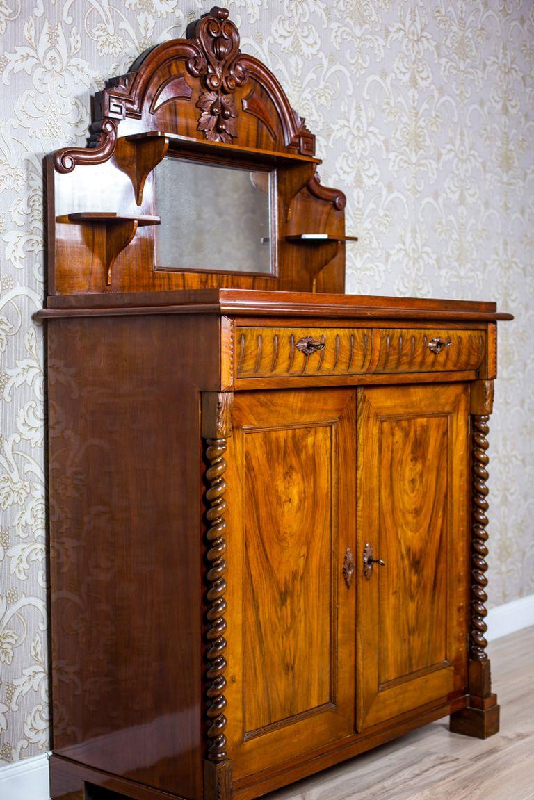 We present you a buffet made of softwood that is veneered with walnut.
The whole is dated fourth quarter of the 19th century.
This piece of furniture is composed of a two-leaf cabinet with two drawers under the top and an upper section in the form