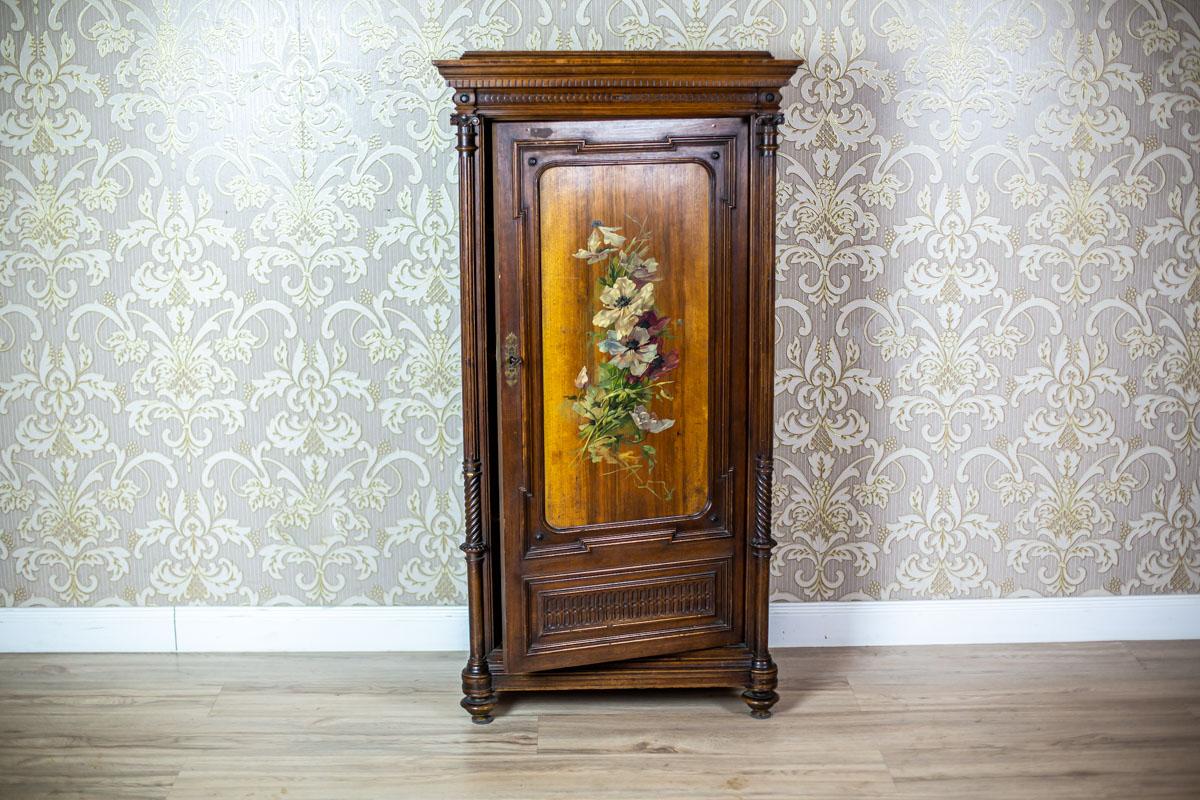 We present you this small, single-leaf chest piece of furniture, topped with a straight cornice.
The door leaf is flanked by columns.
Furthermore, the door panel is painted with a floral motif.
The inside is divided by three shelves.

This