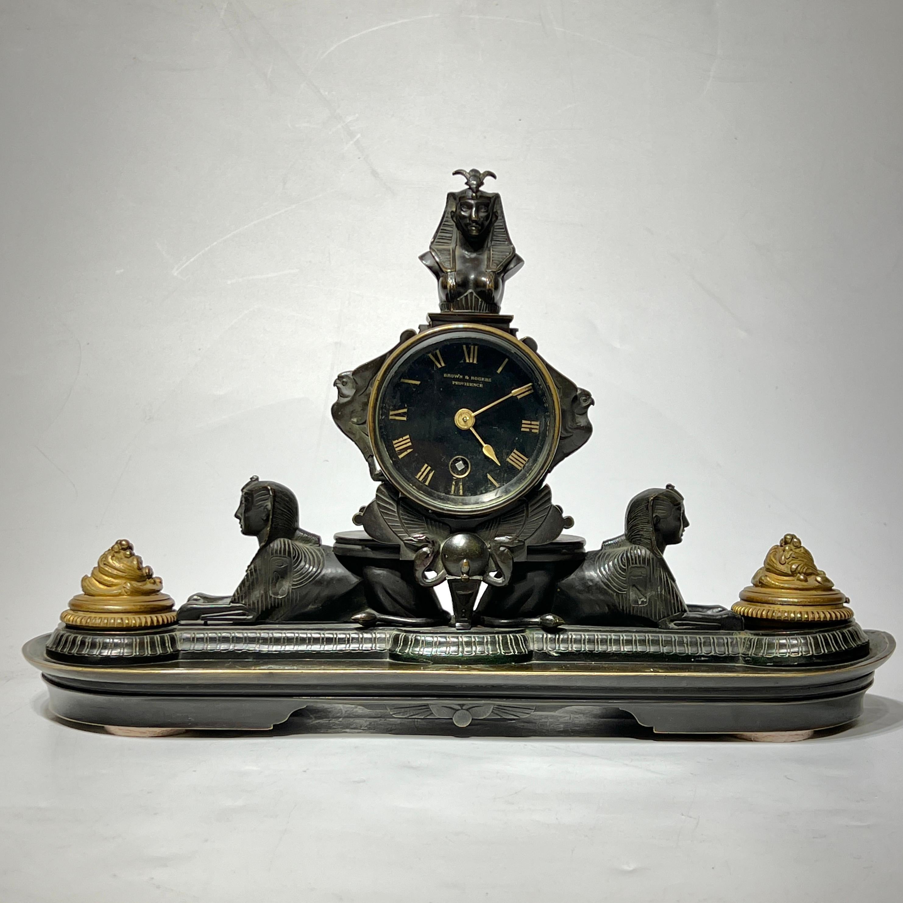 Antique (late 19th century) Egyptian Revival period French empire style mantel clock in bronze with dark brown patina, retailed at Brown and Rogers of Providence, Rhode Island.