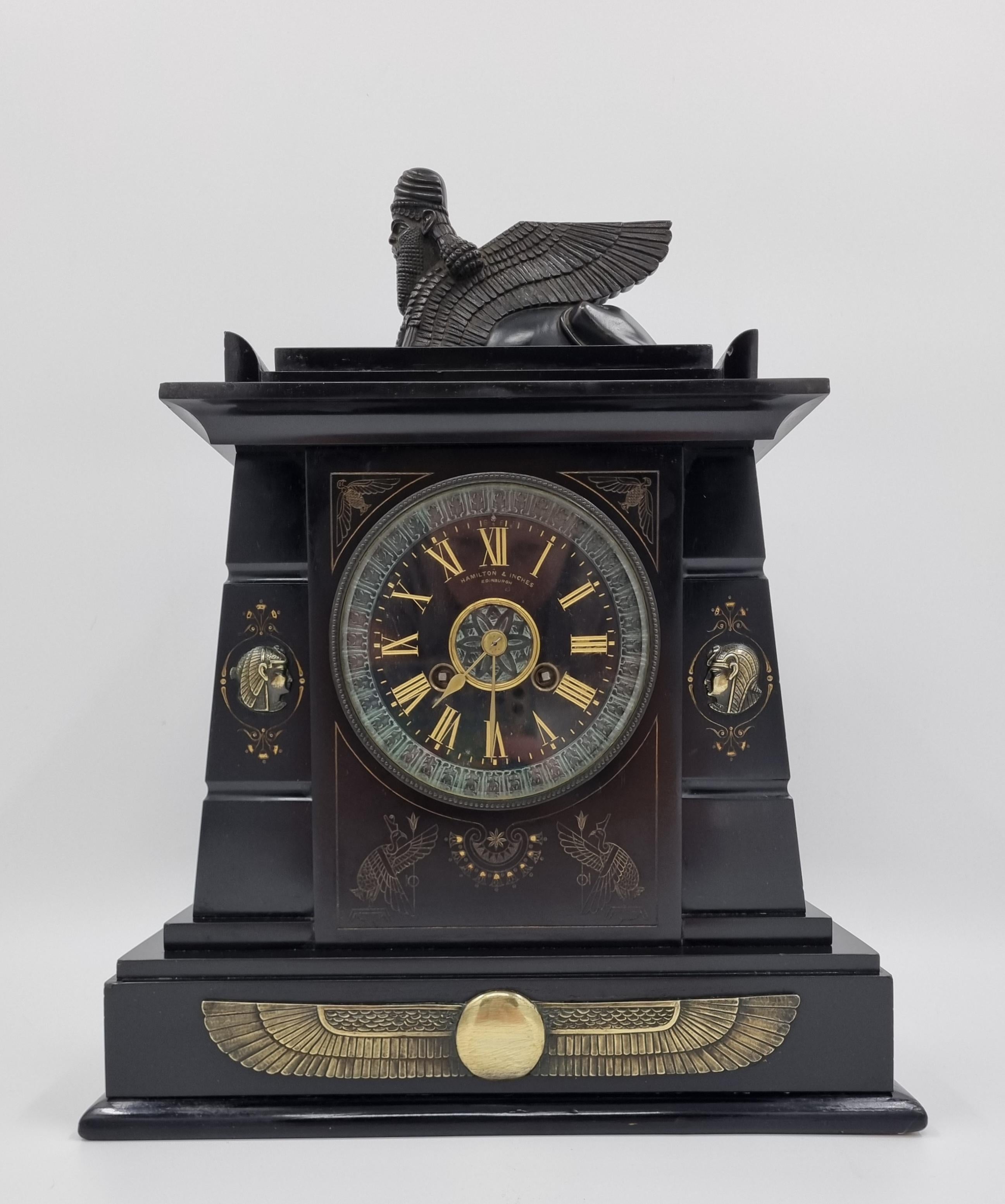 Horloge en marbre noir de style néo-égyptien

Vers les années 1860, fabriquée par les célèbres horlogers et bijoutiers Hamilton and Inches d'Édimbourg, avec un mandat royal accordé par la reine Victoria en 1893. 

Dotée d'un superbe boîtier en