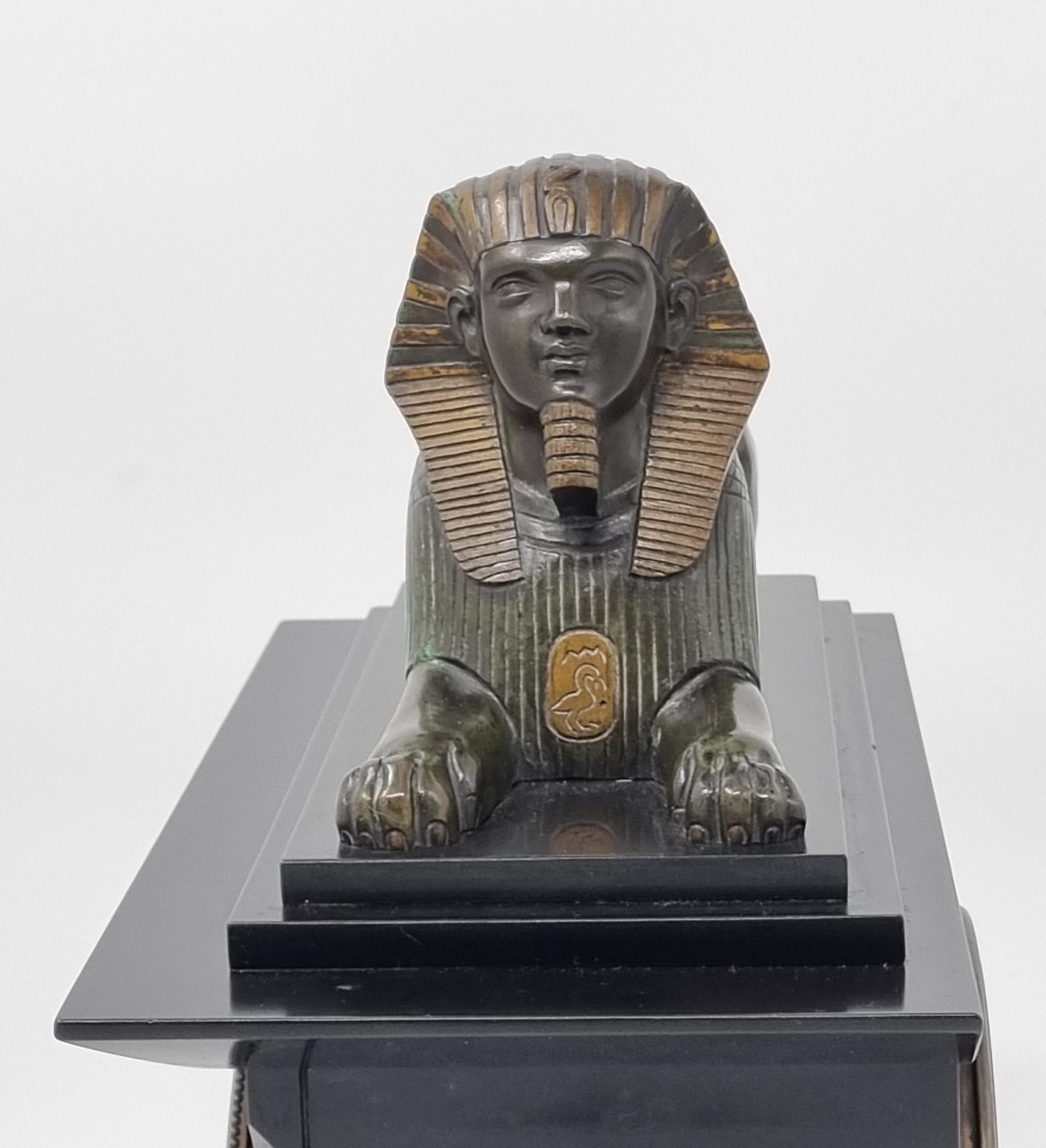An elegant 19th Century Egyptian Revival Clock, black marble , adorned with intricate Egyptian engravings with a bronze sphinx majestically mounted on the top . This exquisite timepiece boasts a sleek and timeless design,  a testament to the