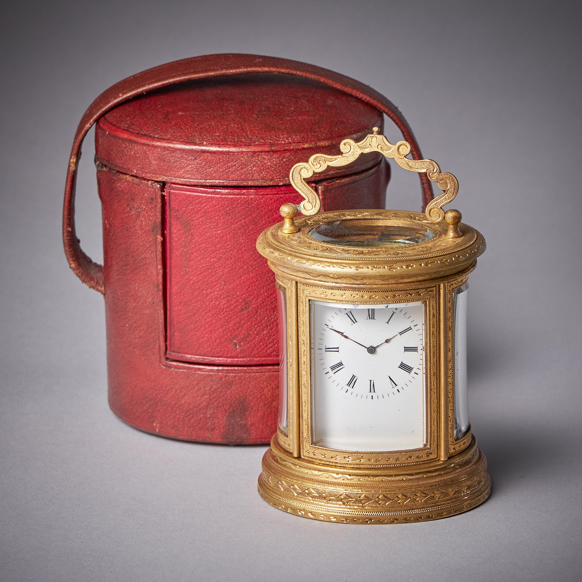 A charming late 19th century French engraved miniature oval carriage clock with original travelling case. 

The petite miniature oval gilt brass engraved case is raised on a triple plinth and has bevelled glass windows on all sides so that the