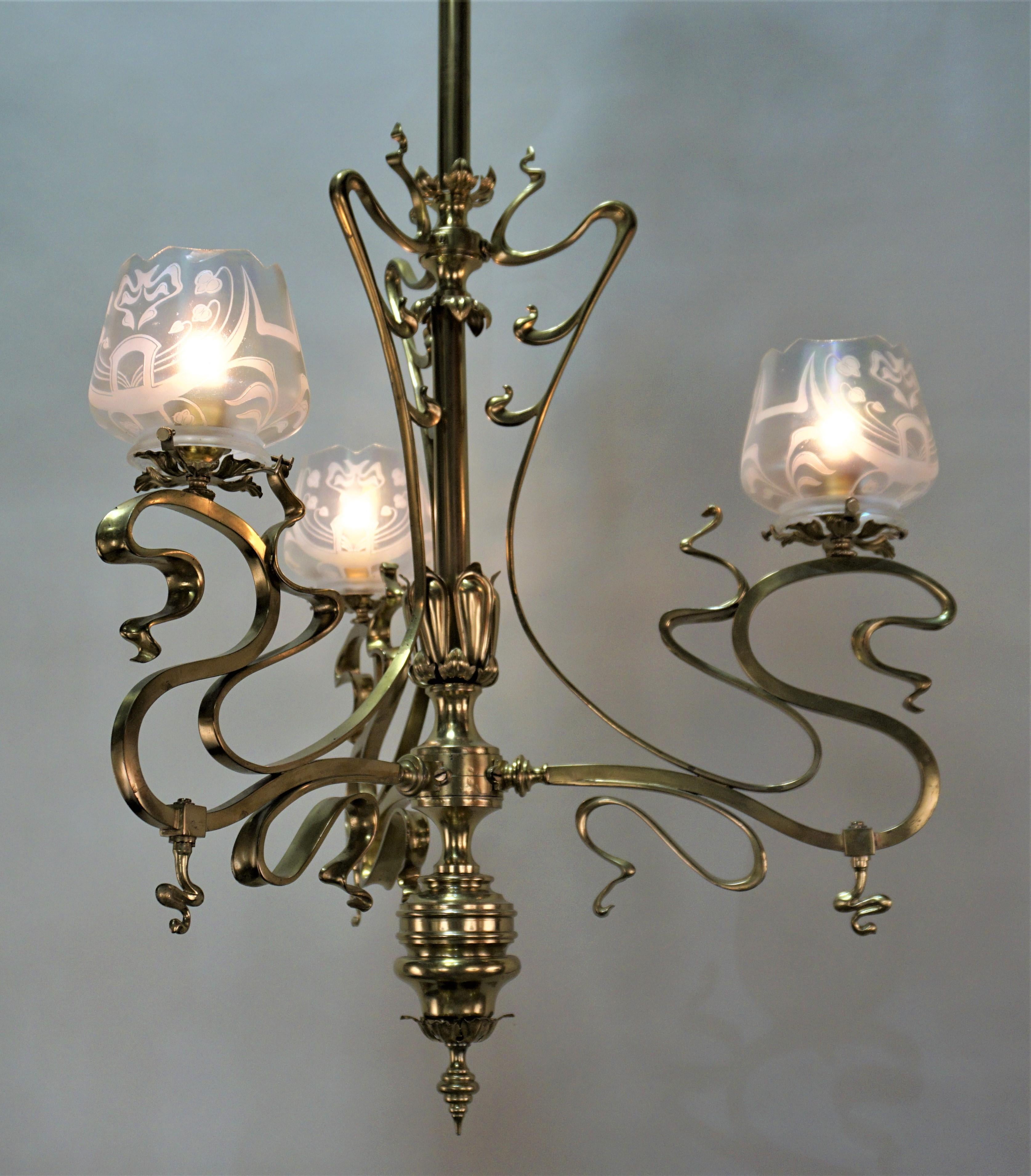 Three-arm 19th century Art Nouveau gas chandelier that has been electrified. This elegant chandelier is satin bronze with hand acid etched glass shades.
Height can be adjusted by cutting the centre tubing.