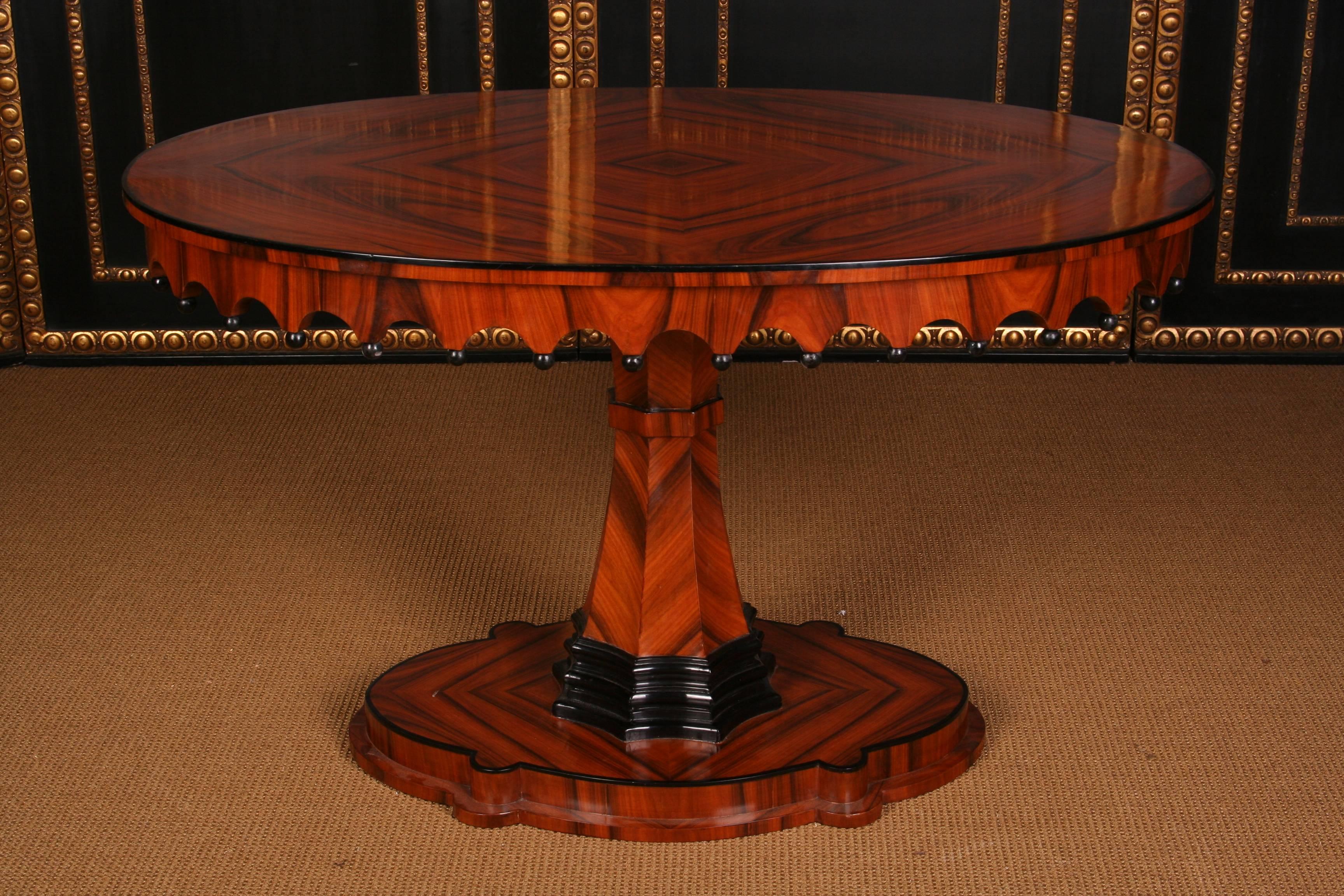 Mahogany on solid wood. Oval curved and profiled base plate. Centrally rising, eightfold folded fan-shaped column, partly blackened. Gothic frame with protruding profile plate. This form is extremely rare. Patina and honey-colored veneer correspond