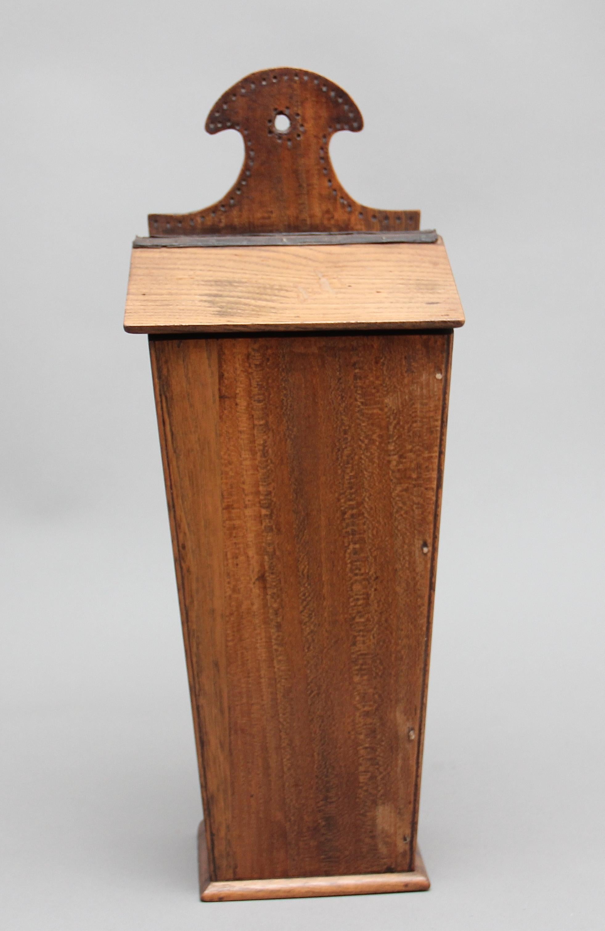 19th century elm and fruitwood candle box of nice design, the shaped top structure above a tilted lift up lid for storing candles, circa 1840.