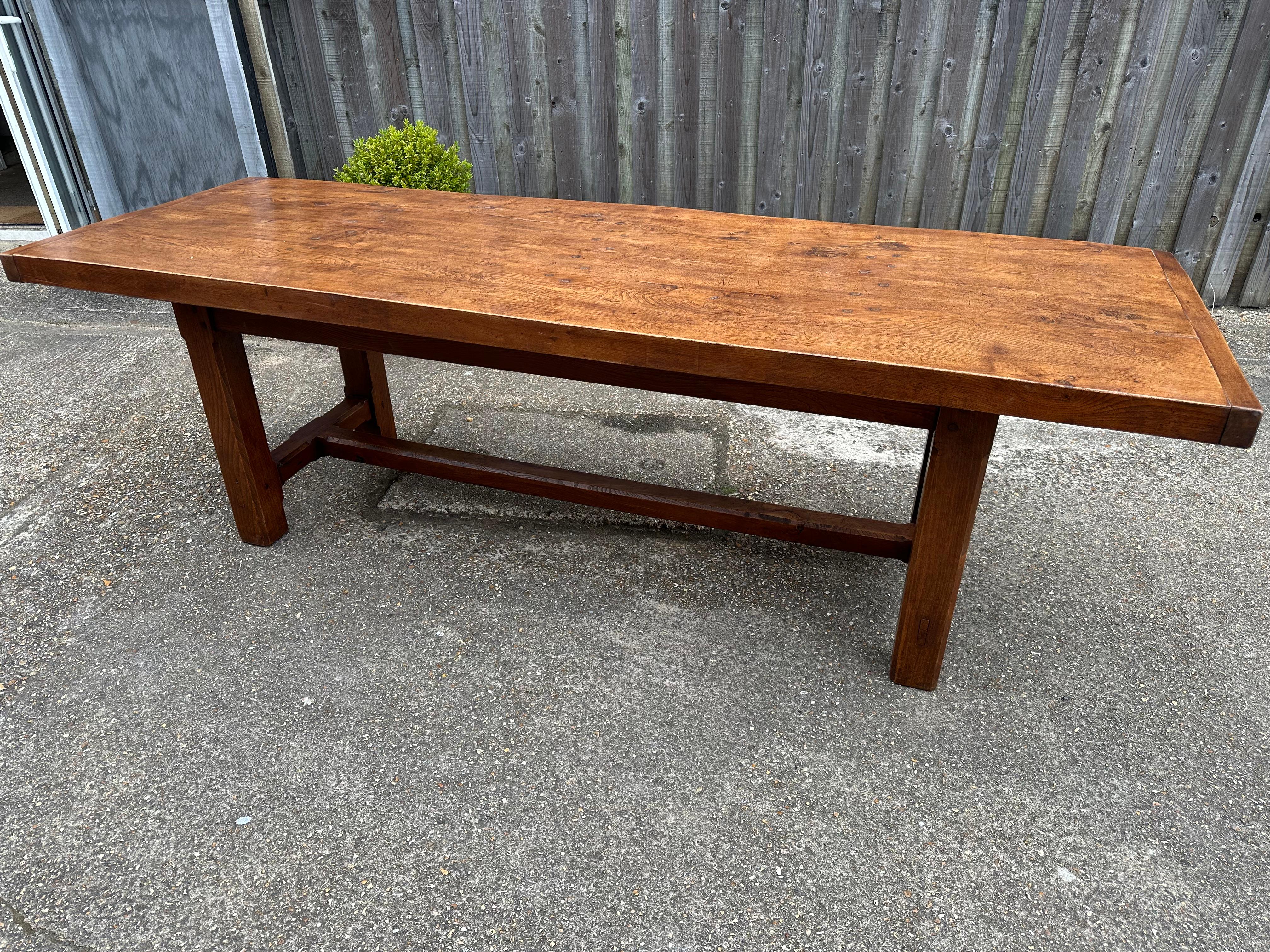 Antique Elm Farmhouse Table with a four plank top and plenty of overhang. The table has an end and centre stretcher. It has good leg room, with a sturdy base and square legs.  Gorgeous patination and colour.  This table would seat 10 people.  