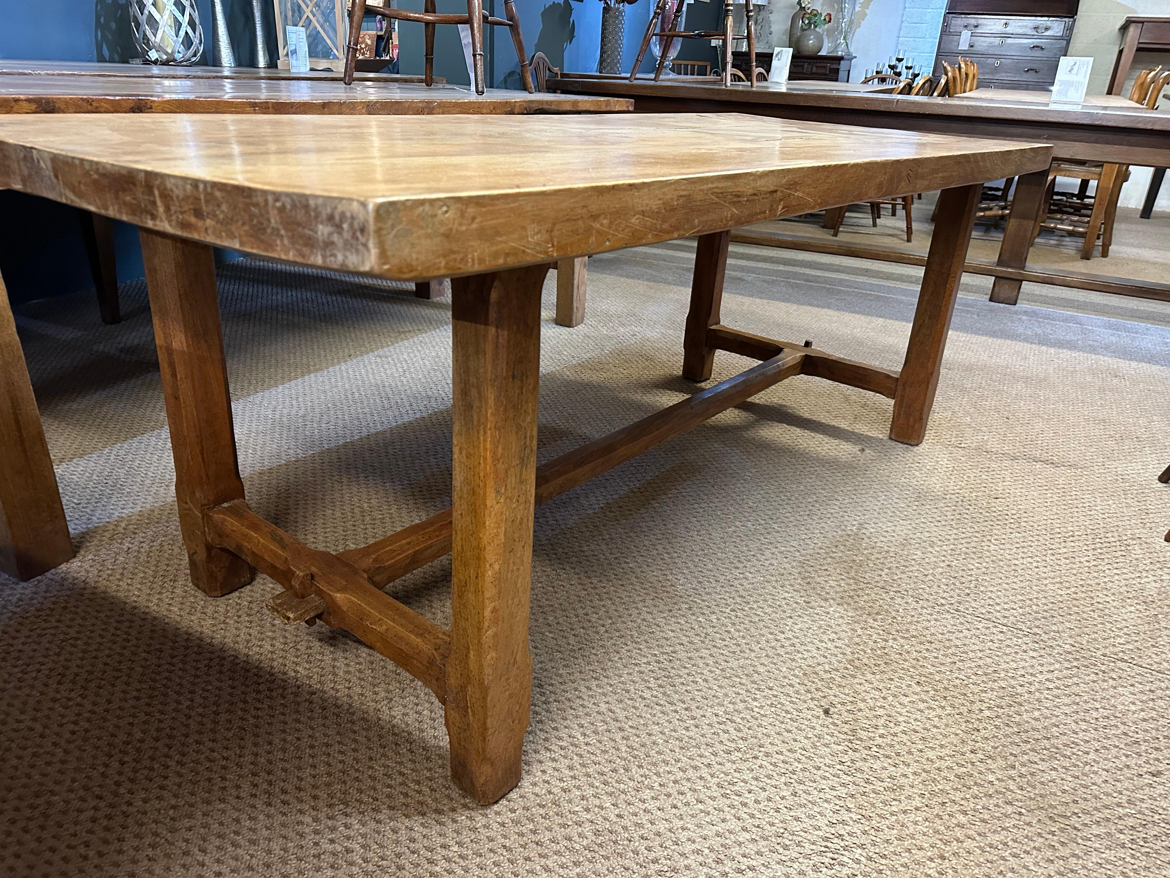 The 19th Century Elm, Normandy table is a stunning piece of furniture. It features two end stretches and a top made of three wide planks. The table has a beautiful patinated finish, which adds to its charm. The wood used in the table has lovely